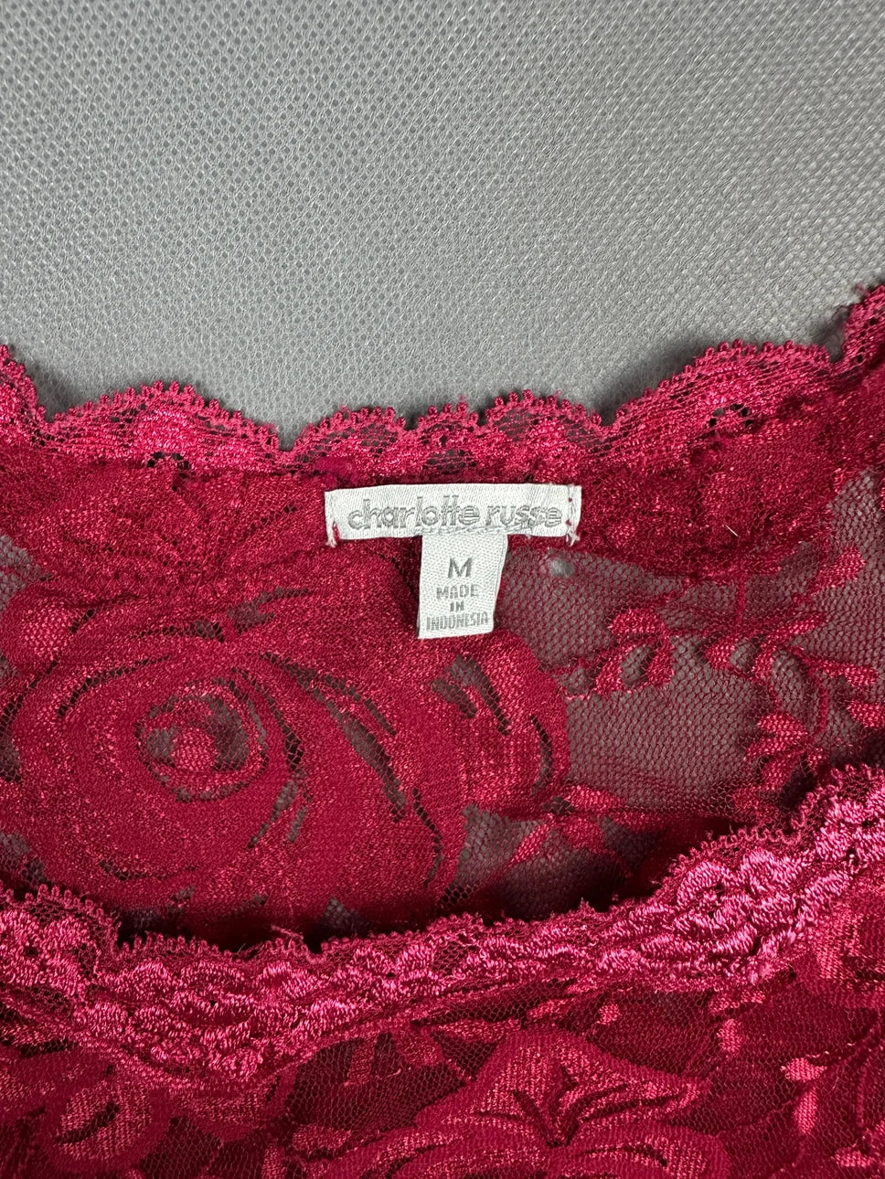 Detail view of a burgundy lace top with floral pattern.