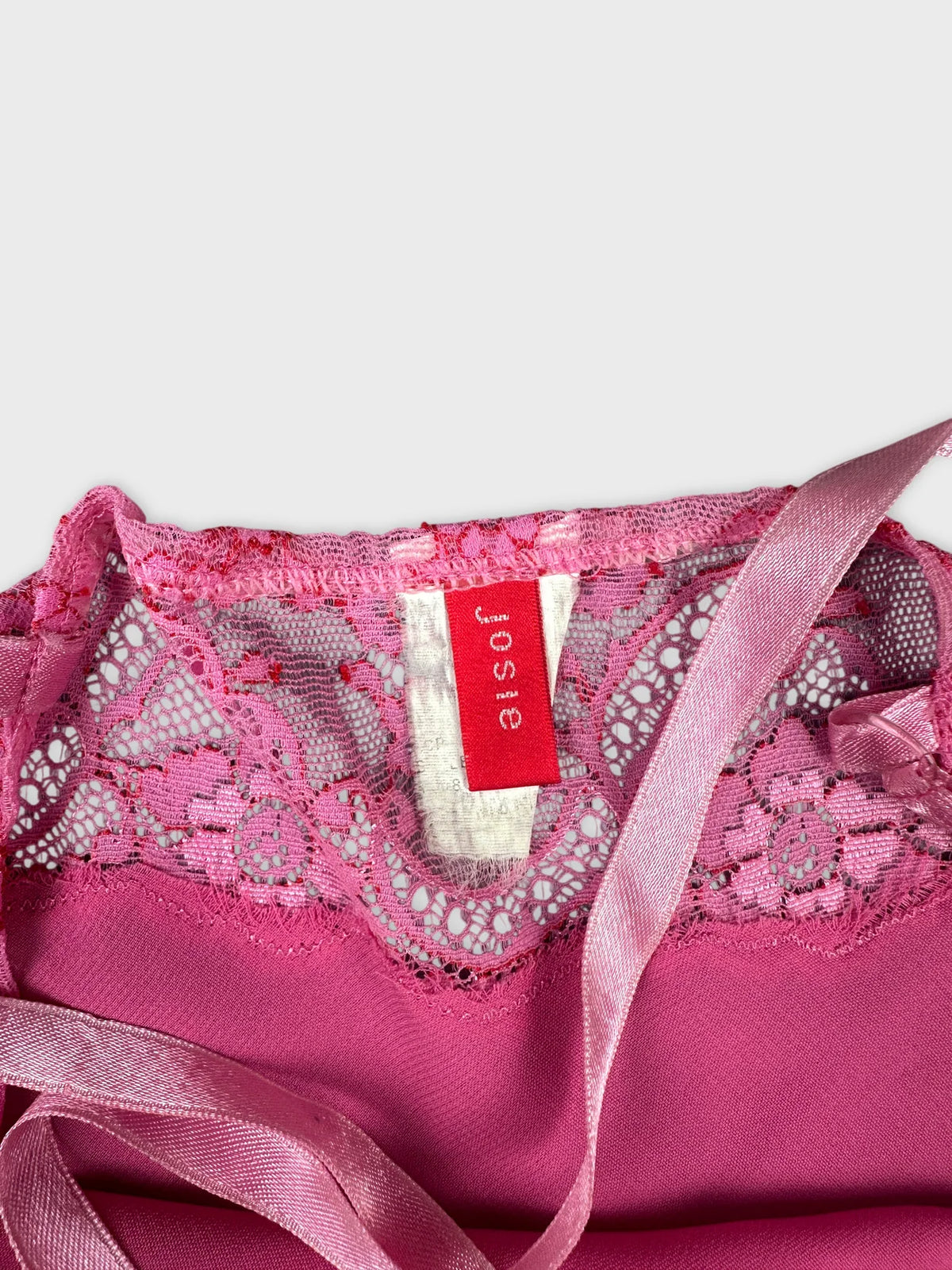 Detail view of a pink top featuring lace trim and satin straps.