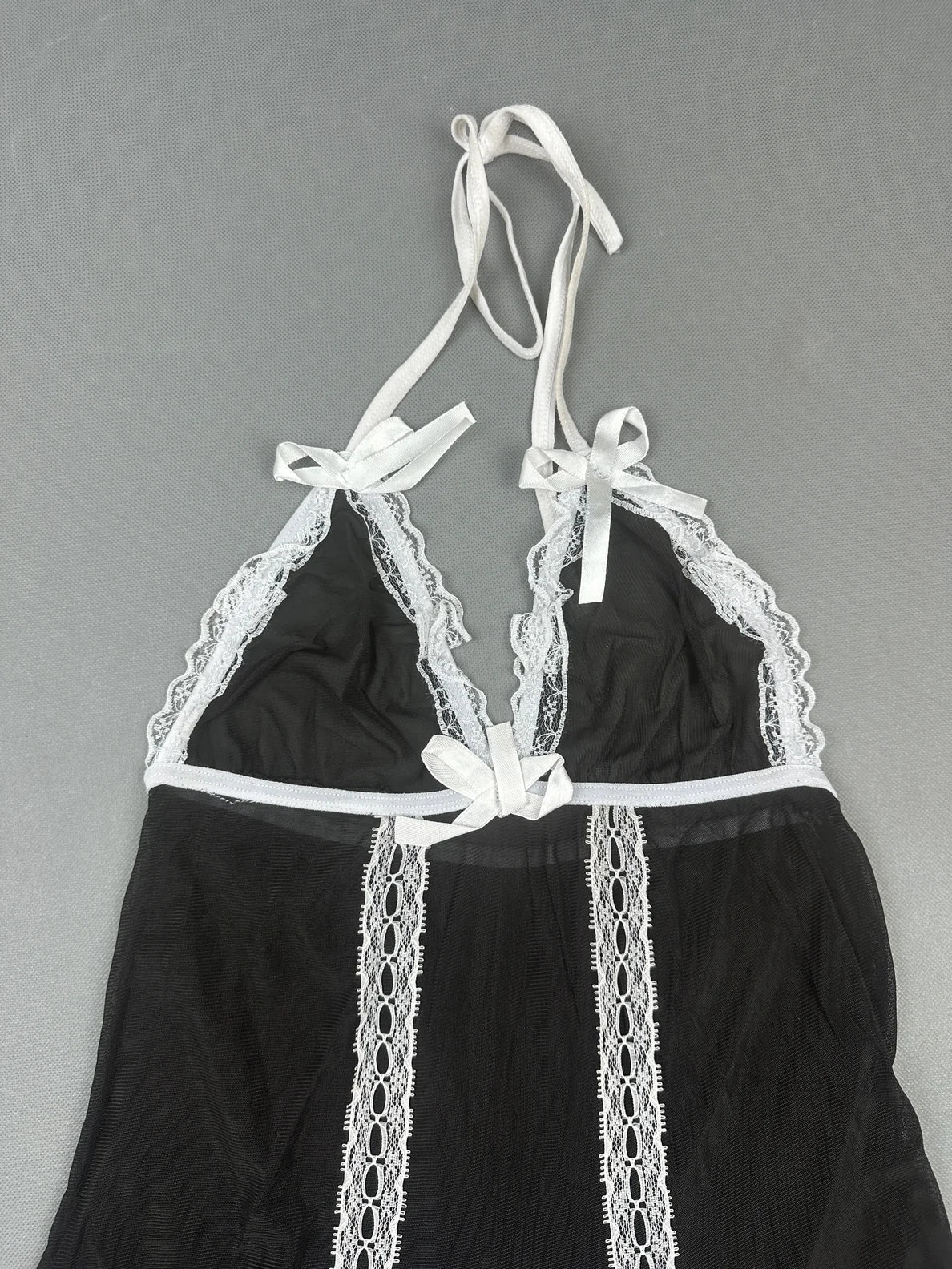Detail view of a black halter top with white lace trim.
