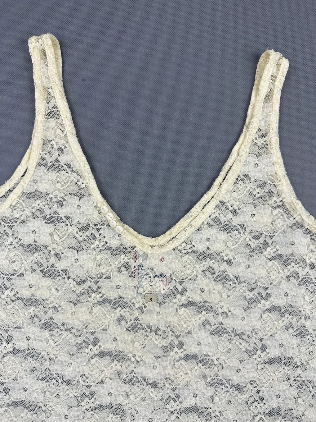 Detail view of a women's vintage lace top in cream color.