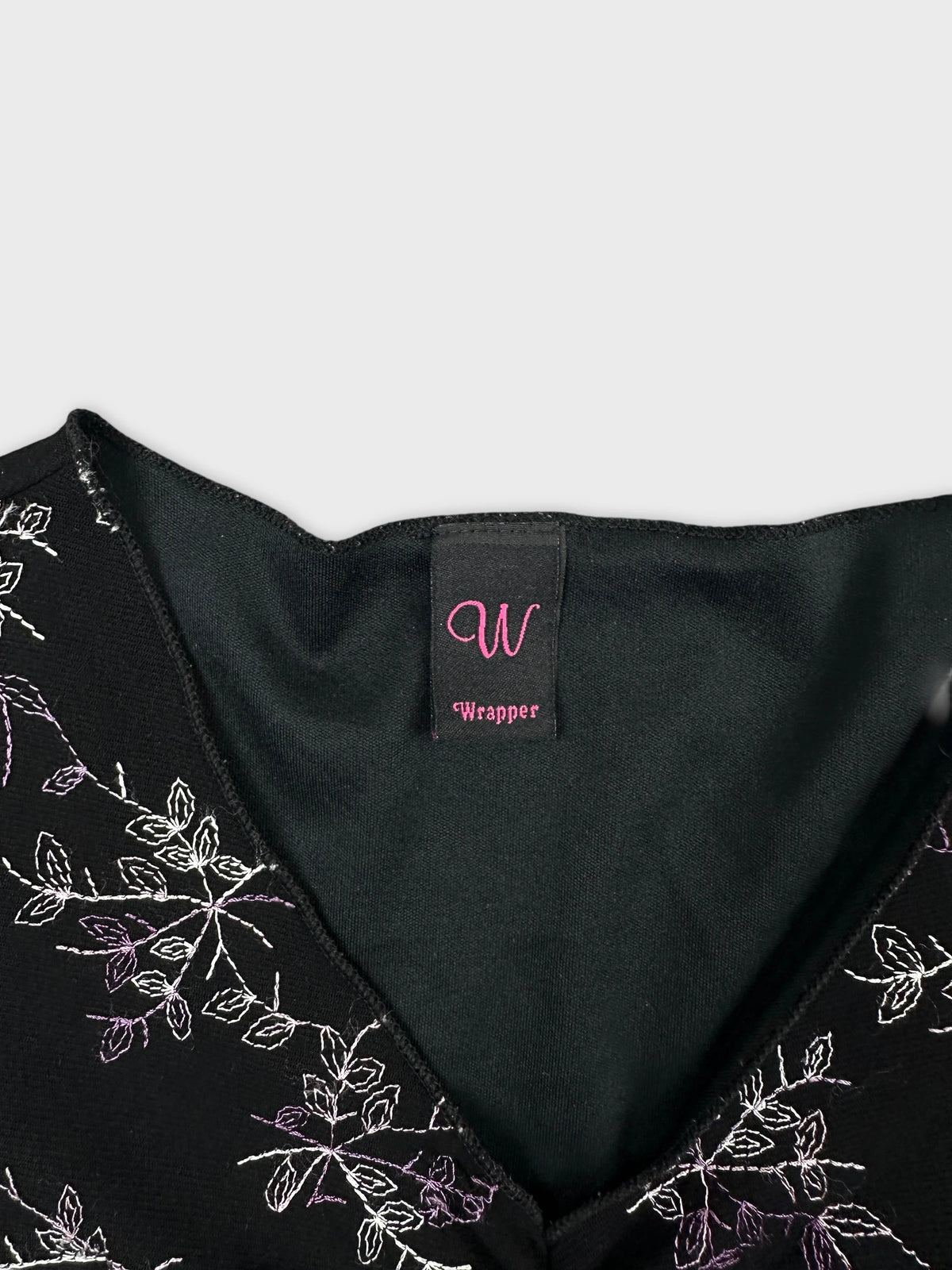 Detail view of a black top with floral embroidery and v-neck.