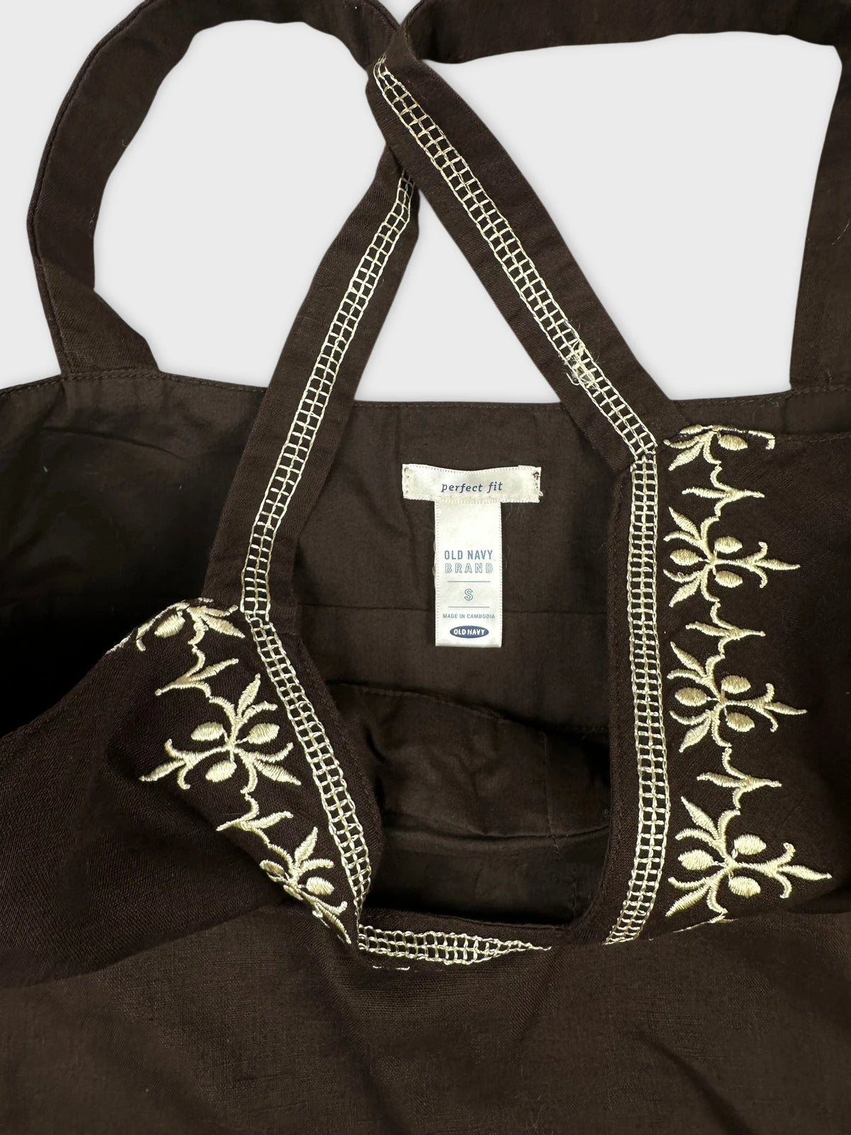 Detail view of a brown women's top featuring floral embroidery.