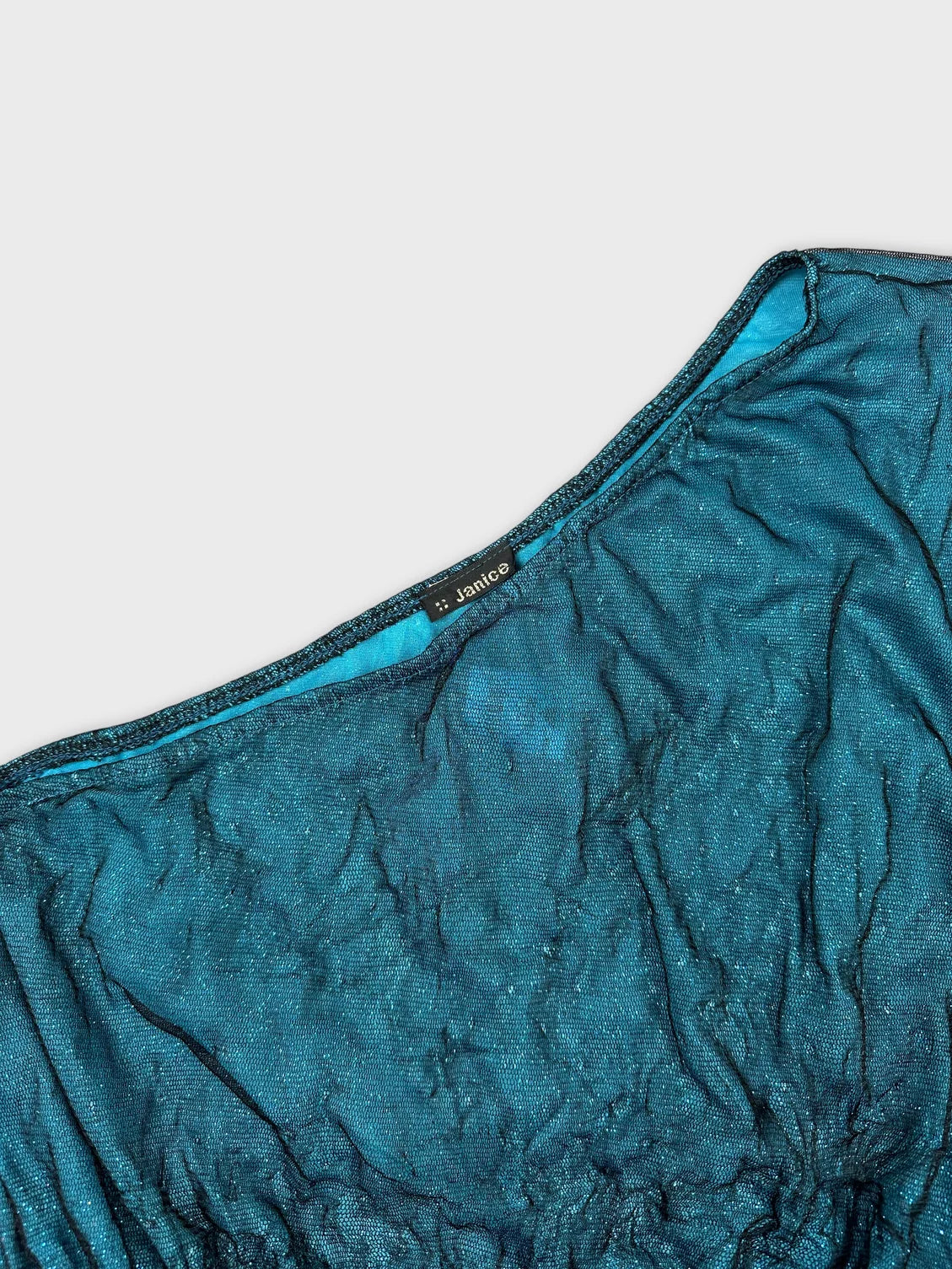 detail view of a women's upper body top in teal with crinkled texture