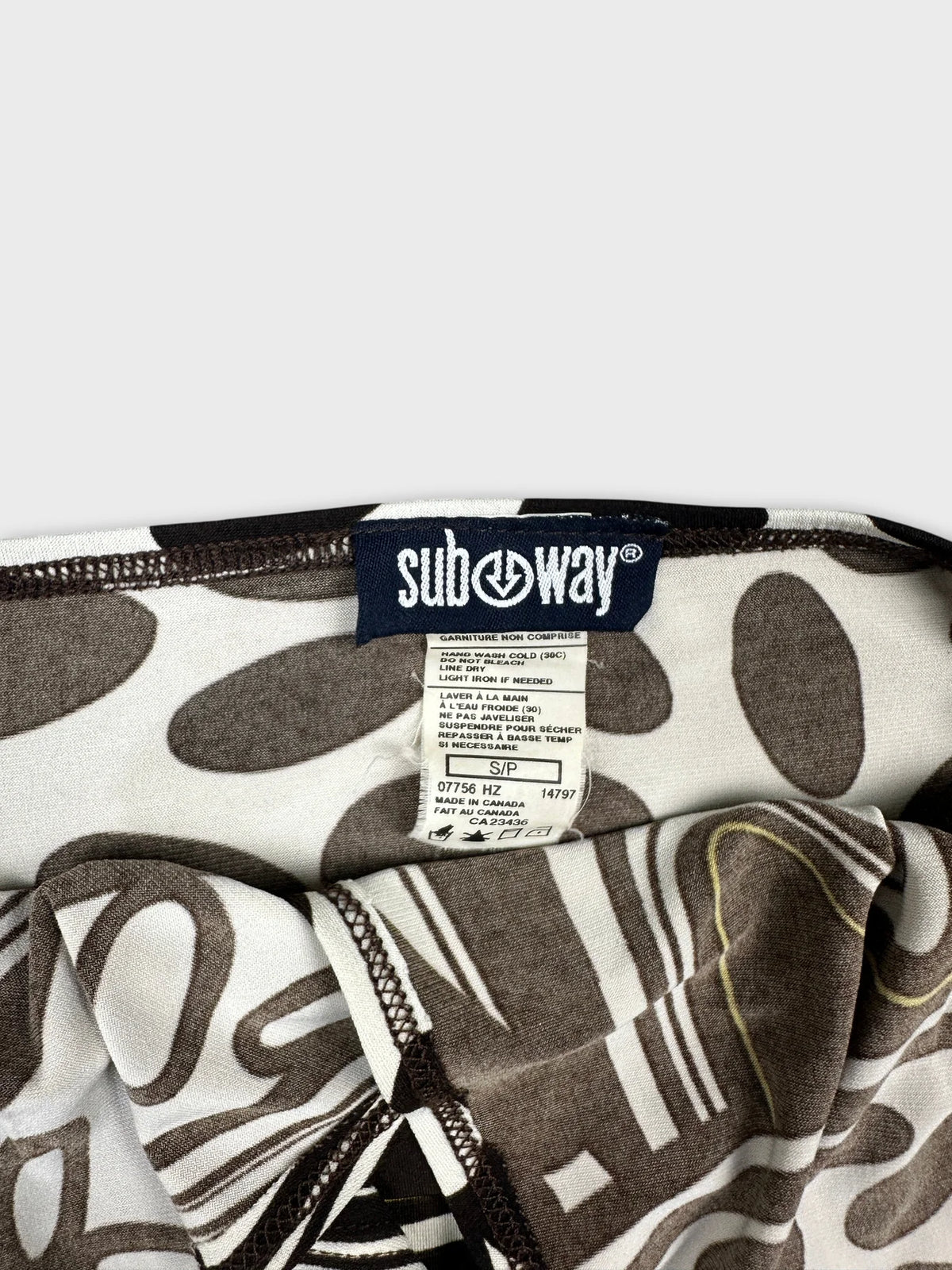 Detail view of a vintage women's top in white and brown with abstract print.
