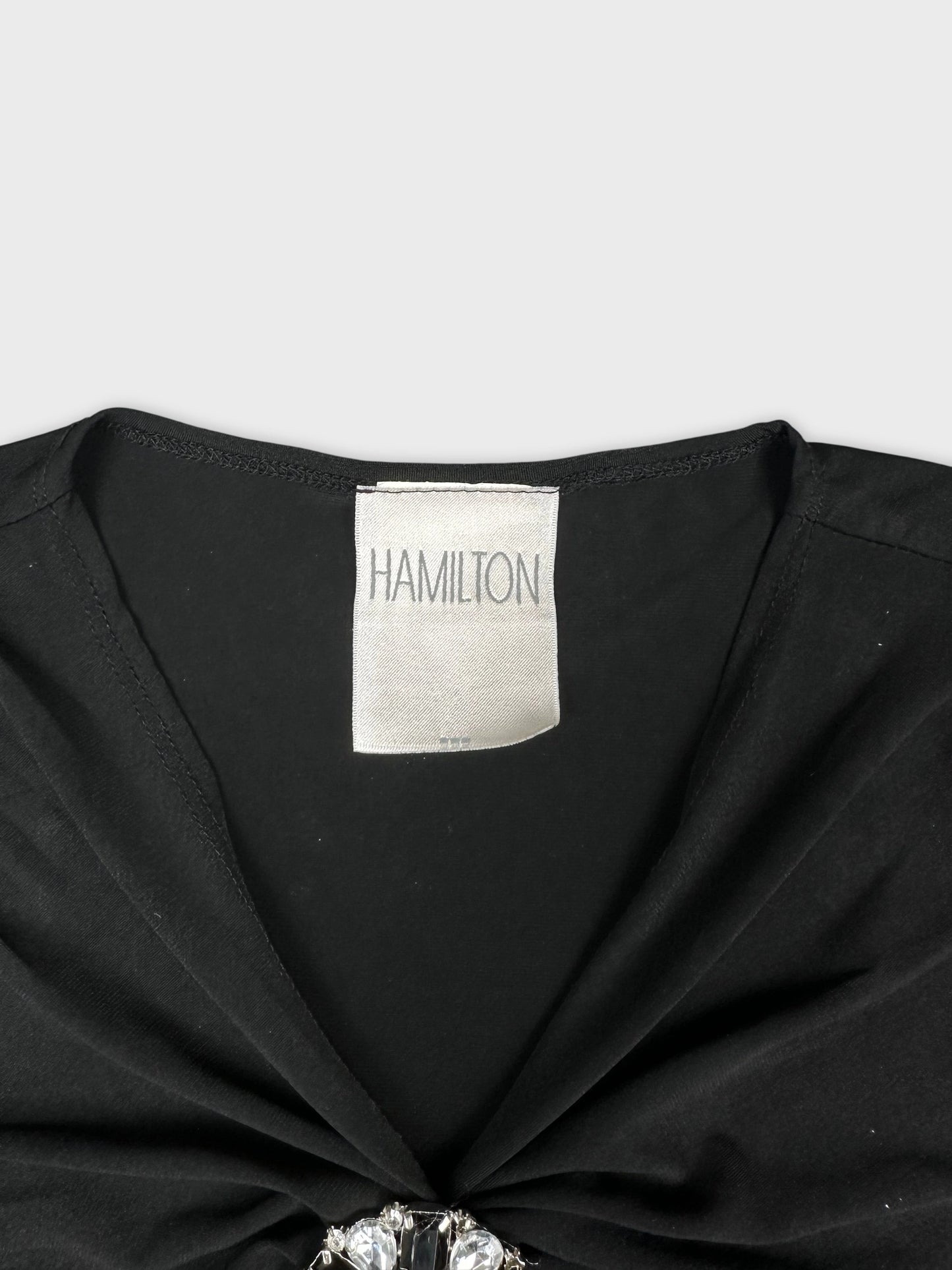 Detail view of a black top featuring a decorative gem brooch.