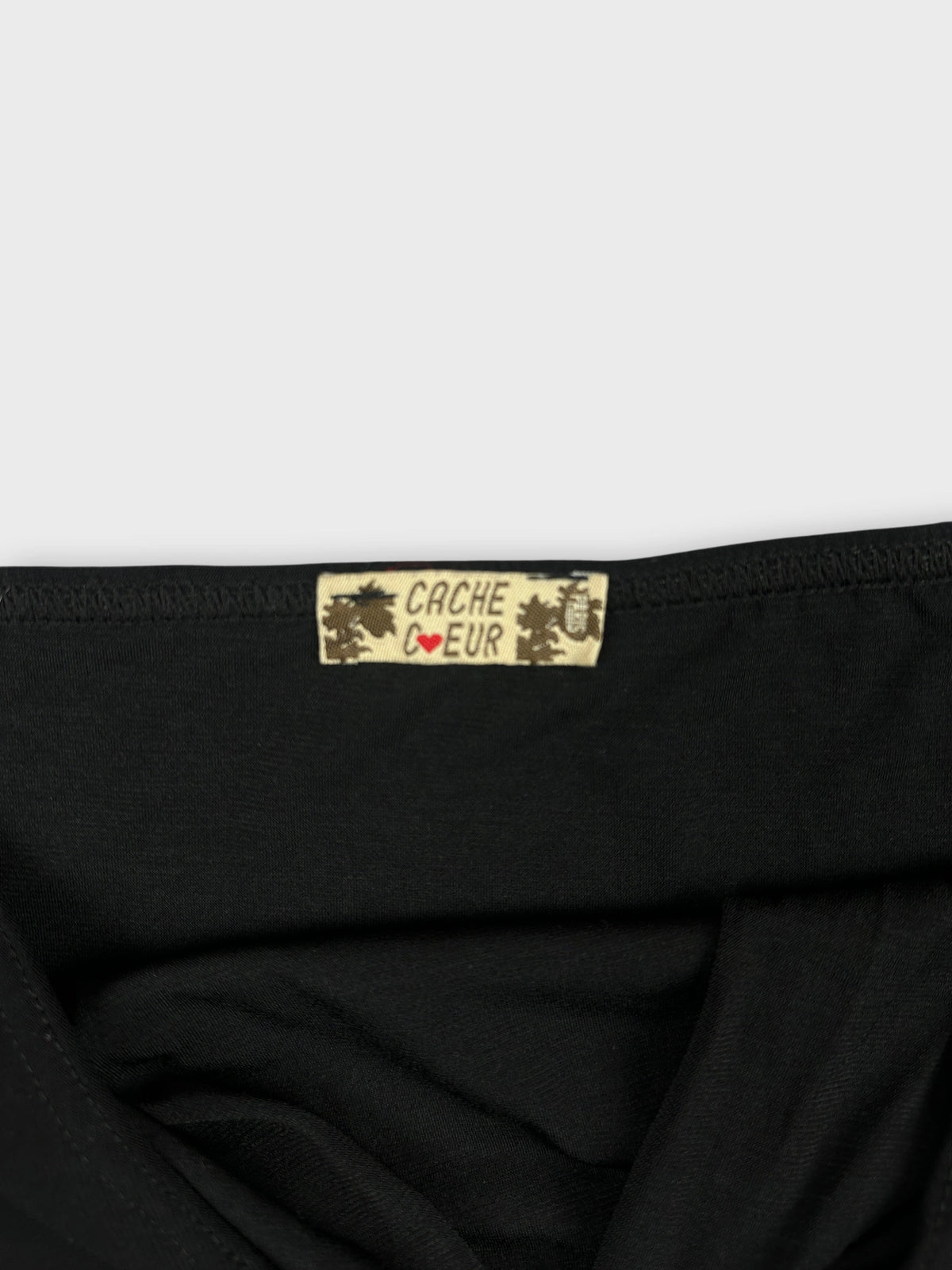 Detail view of a black women's top featuring a Cacheur label.
