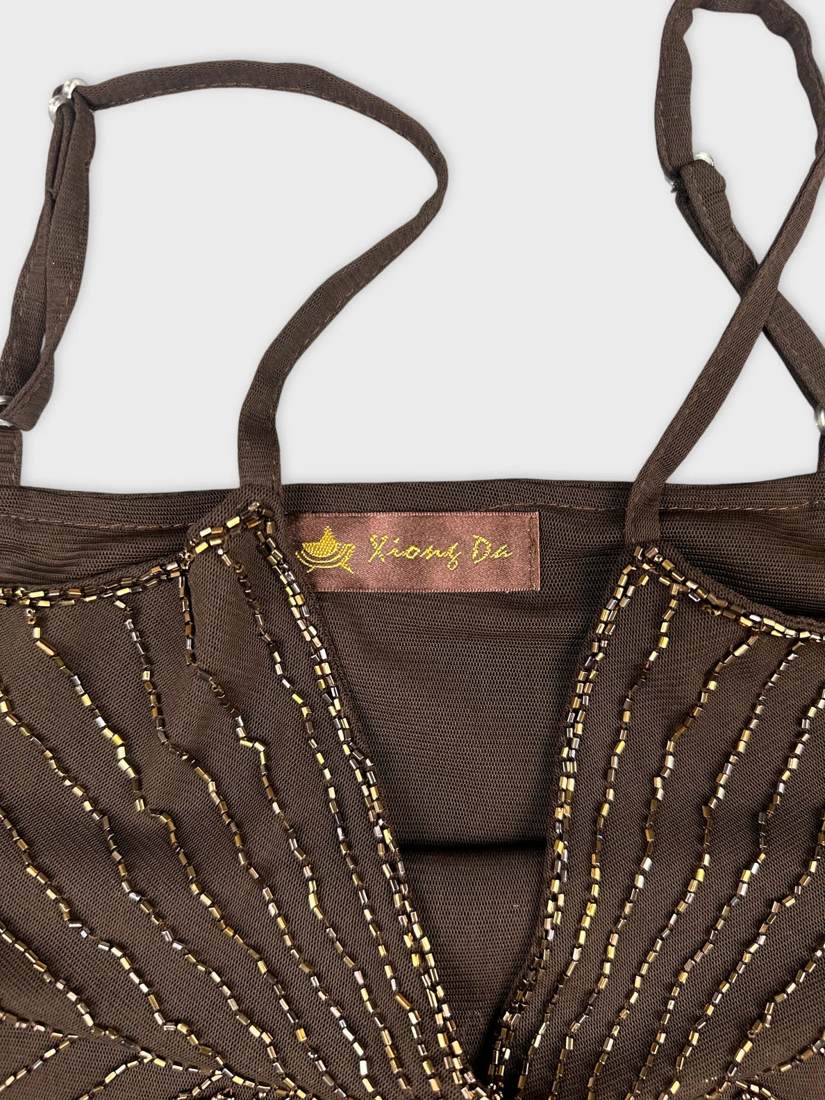 Detail view of a brown top featuring decorative gold beading design.