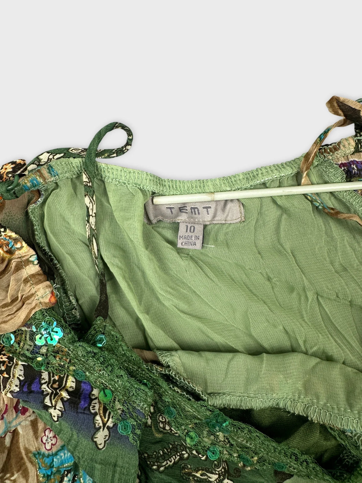 Detail view of vintage green top featuring decorative sequins and lace trim.