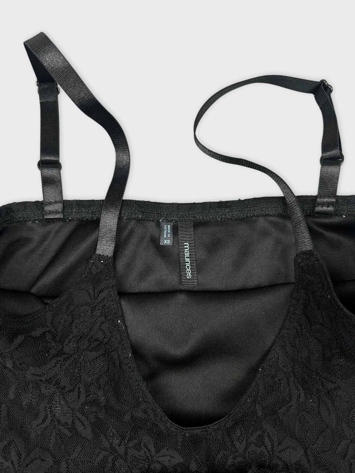 Detail view of a black lace trim camisole with adjustable straps.