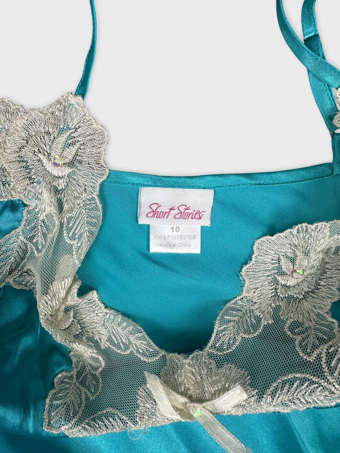 Detail view of a turquoise top with lace floral trim.