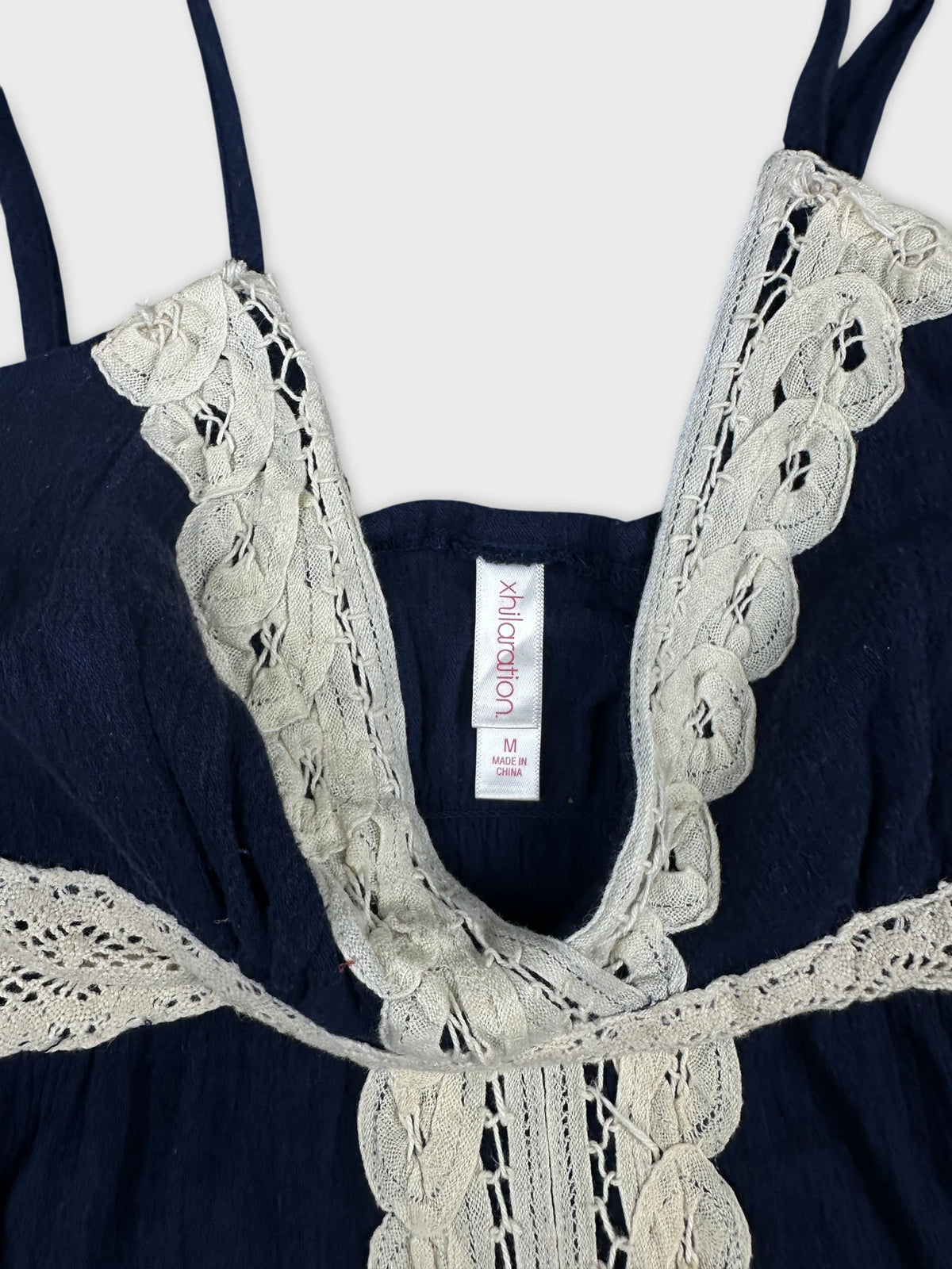 Detail view of a navy upper body top featuring intricate lace trim.