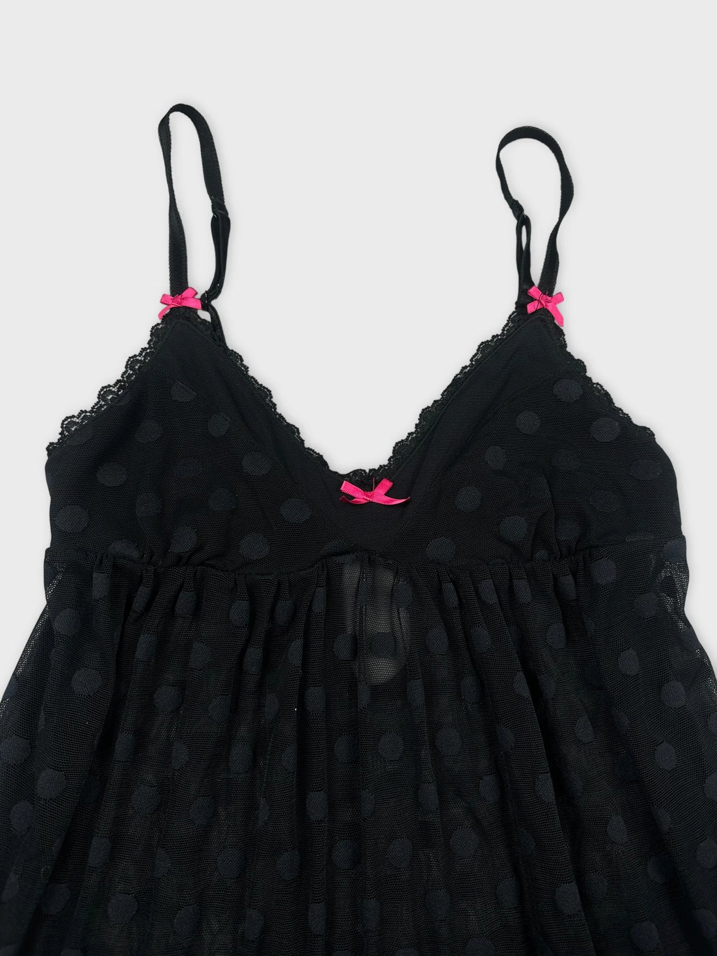 Detail view of a black polka dot camisole with pink straps.