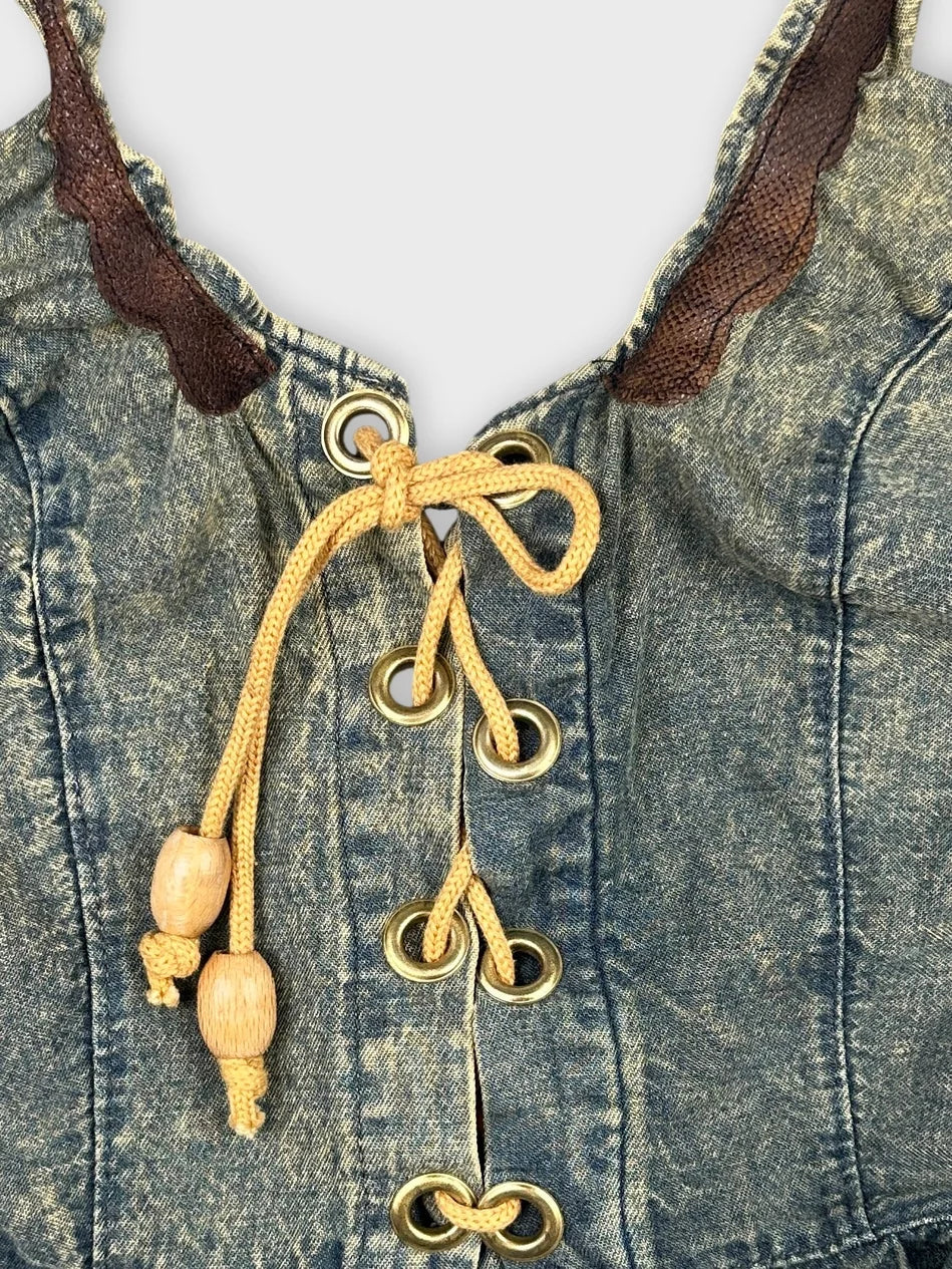 Detail view of a blue denim top with gold eyelets and yellow drawstring