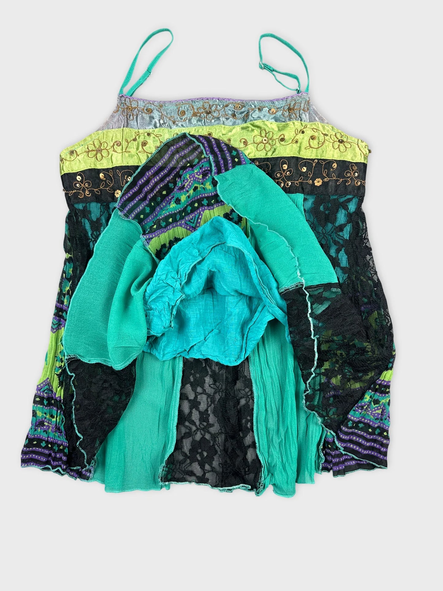 Detail view of a vintage women's top in teal with lace and patterned sections.