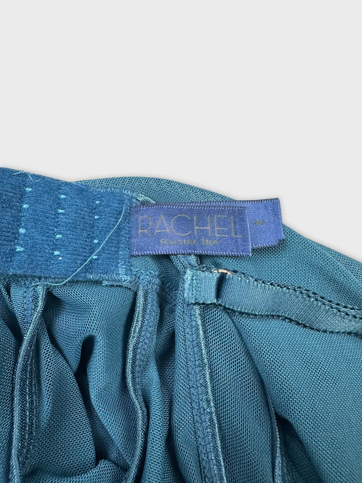 Detail view of a teal upper body top featuring gathered fabric.