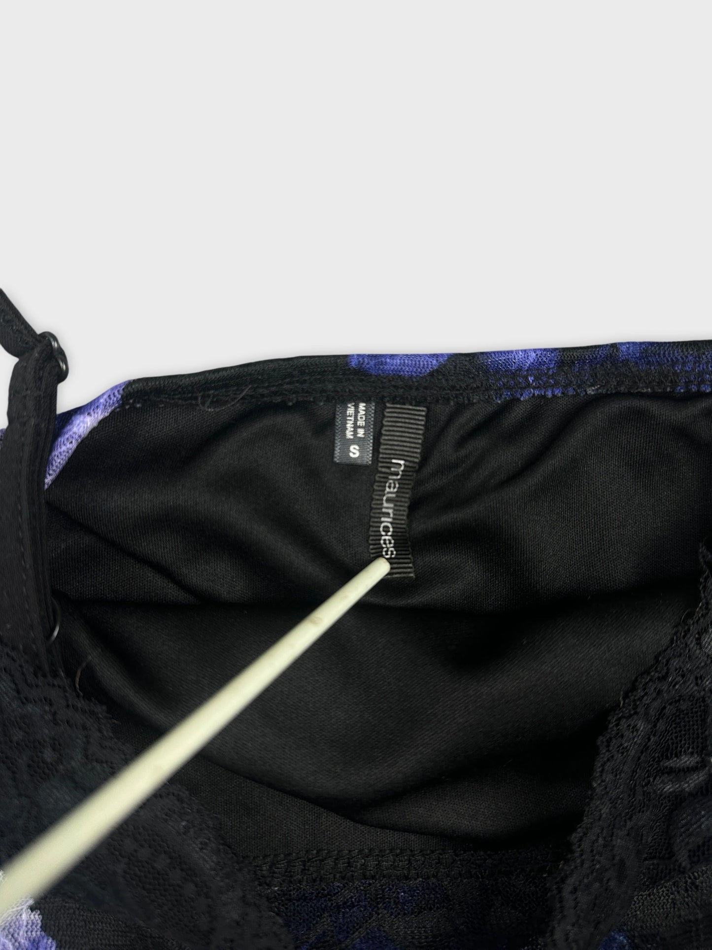 Detail view of a vintage women's top featuring a purple pattern and black lace trim.
