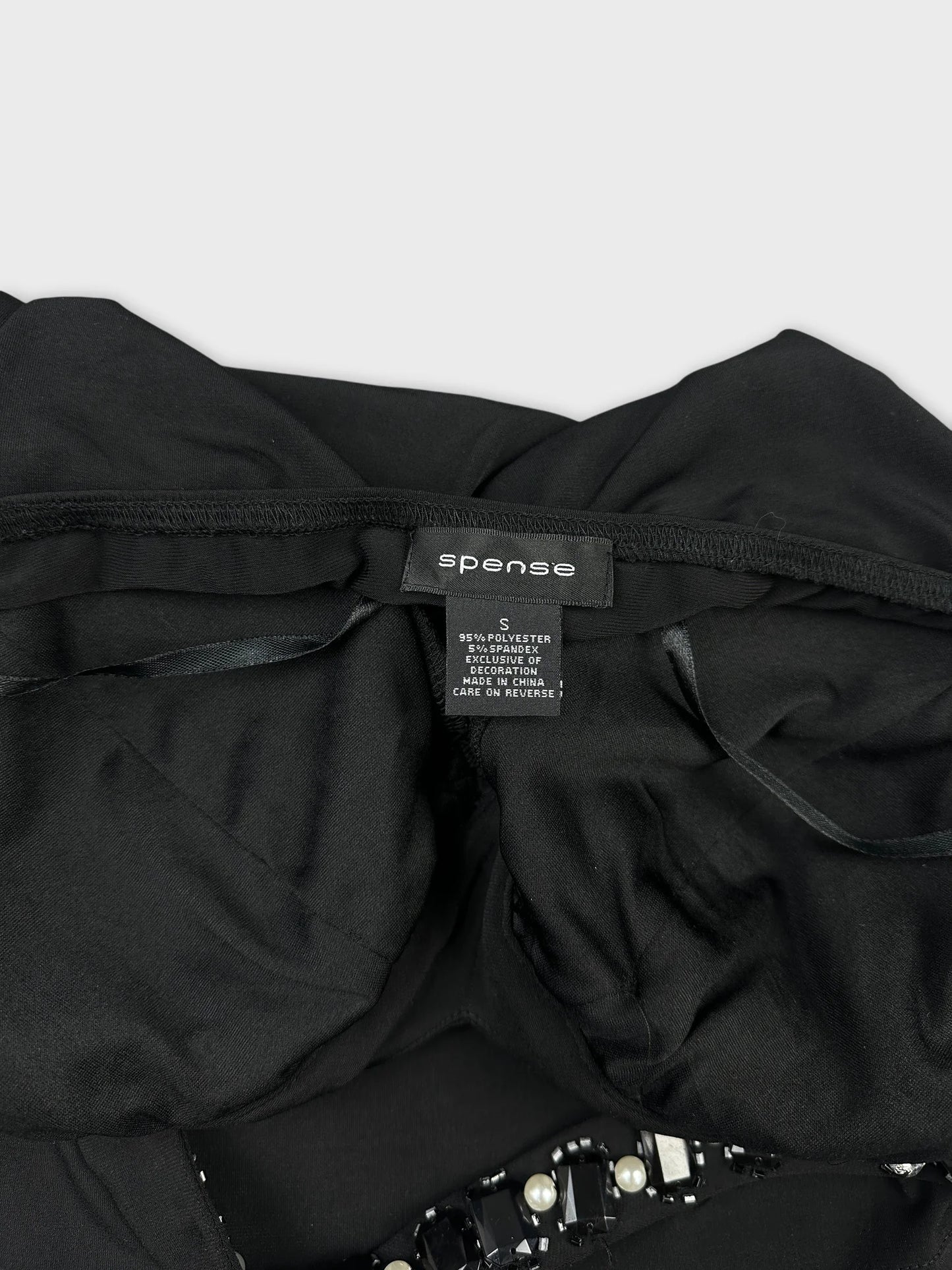 Detail view of black top featuring decorative bead embellishments.