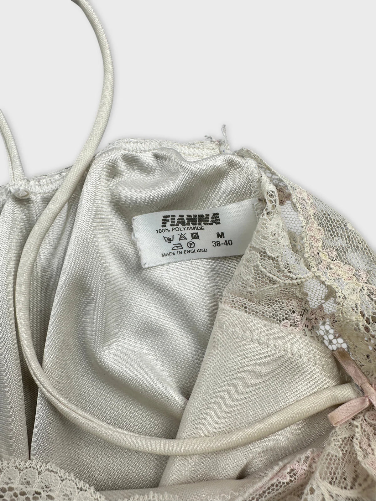 Detail view of a vintage women's top in beige featuring lace trim.