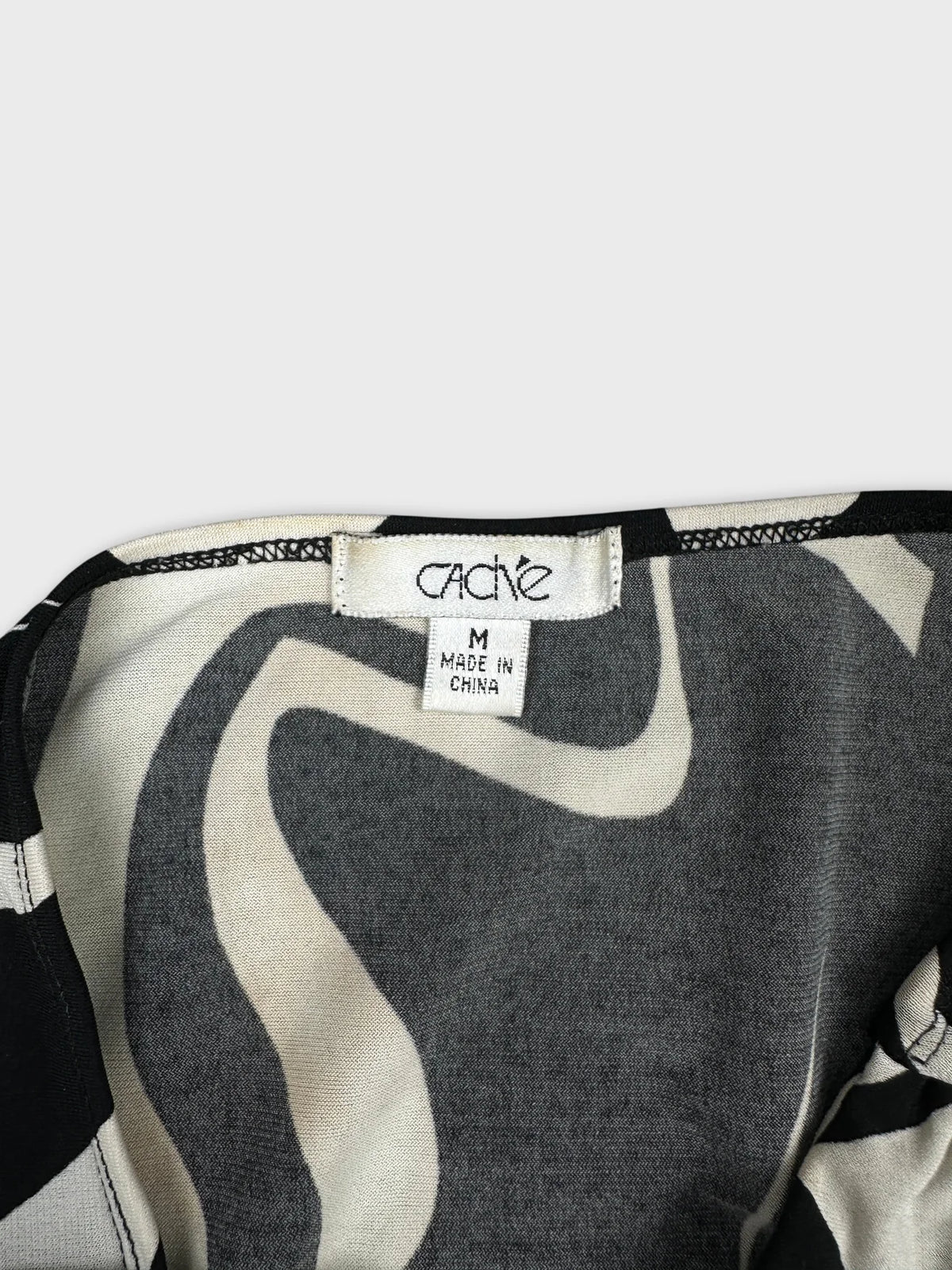 Detail view of a vintage women's top in grey with swirled patterns.