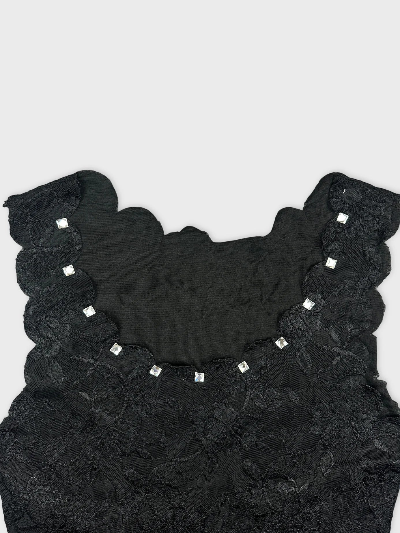 Detail view of a black women's top with lace and gem trim.
