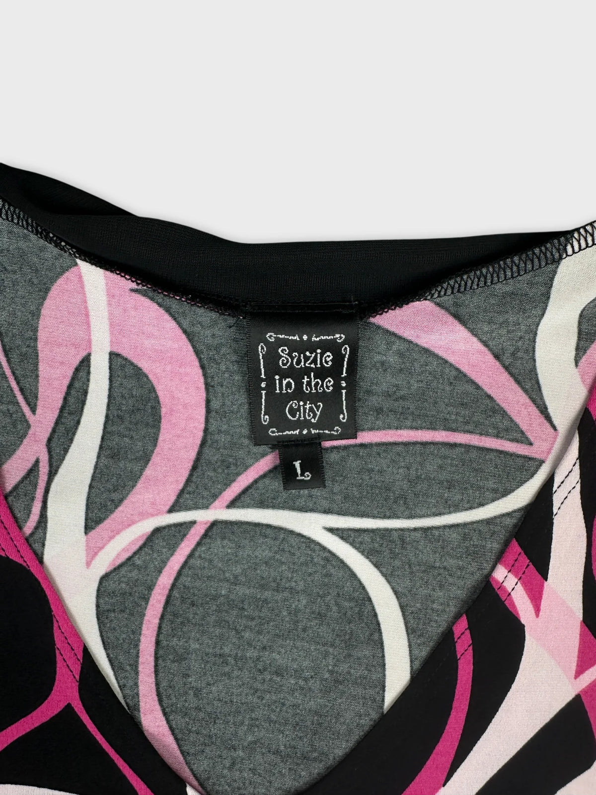 Detail view of a gray women’s top with pink and white swirl pattern.