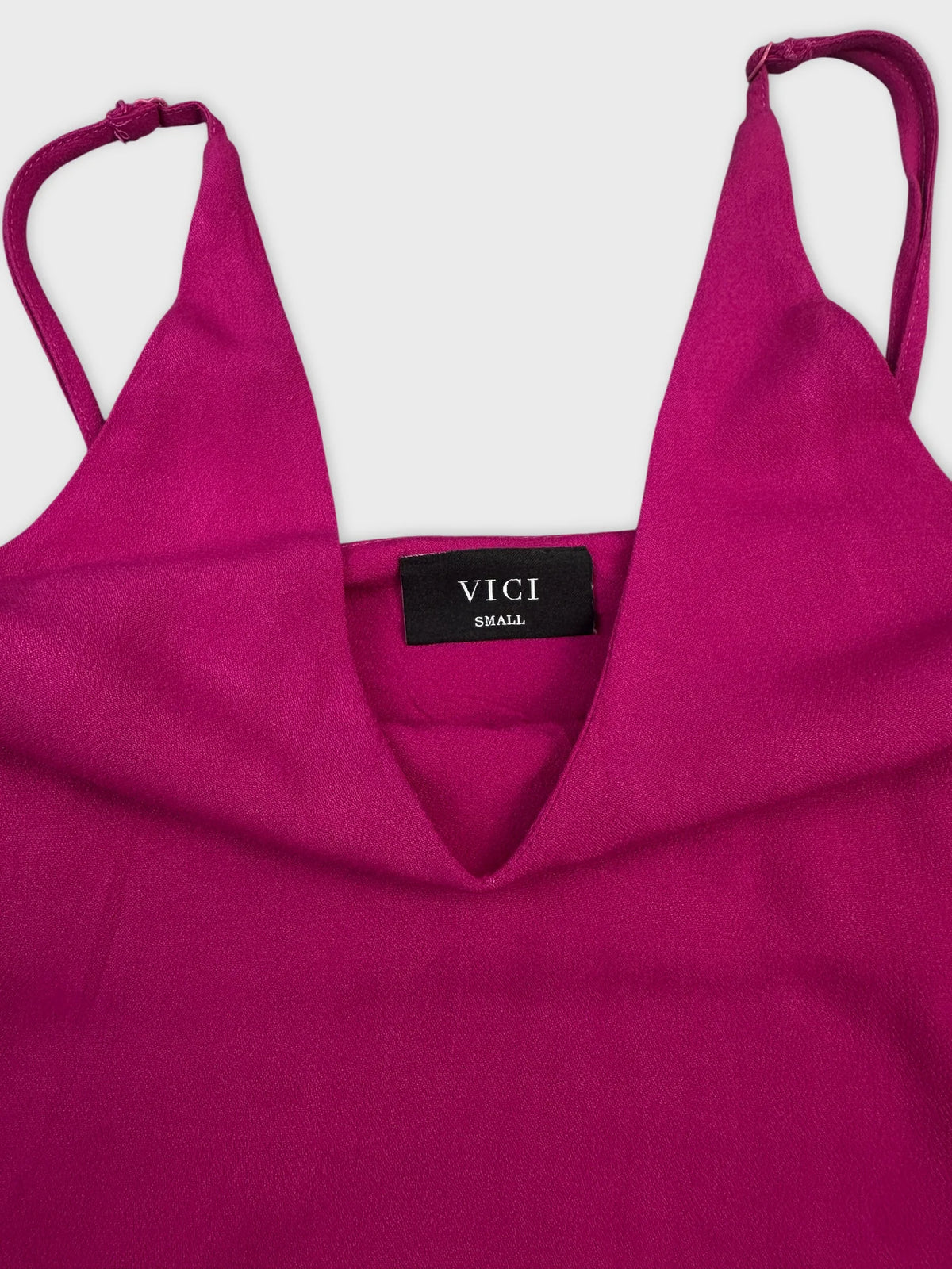 Detail view of a women's top in vibrant magenta with a V-neck design.