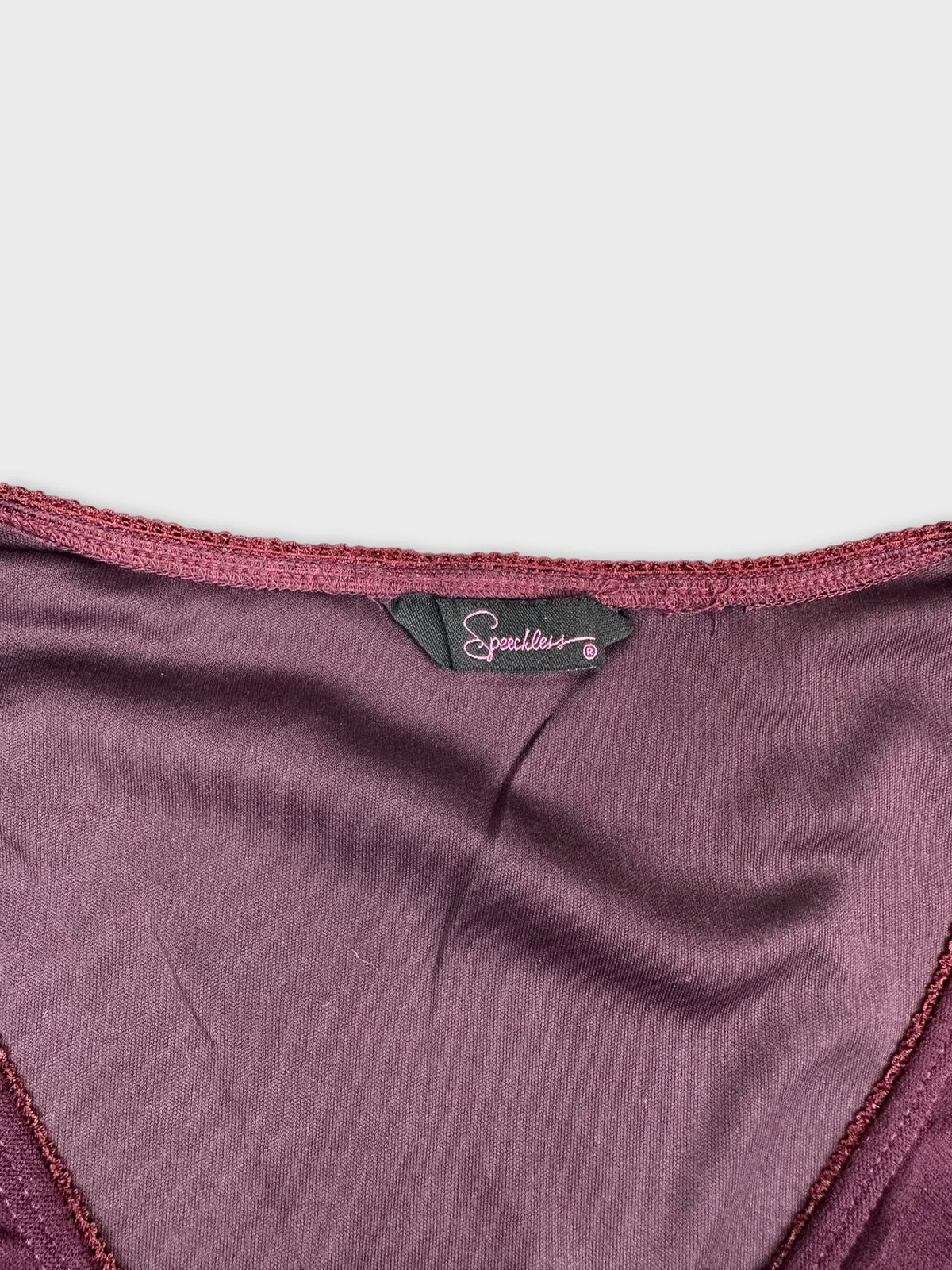 Detail view of a maroon women’s upper body top with a smooth neckline.