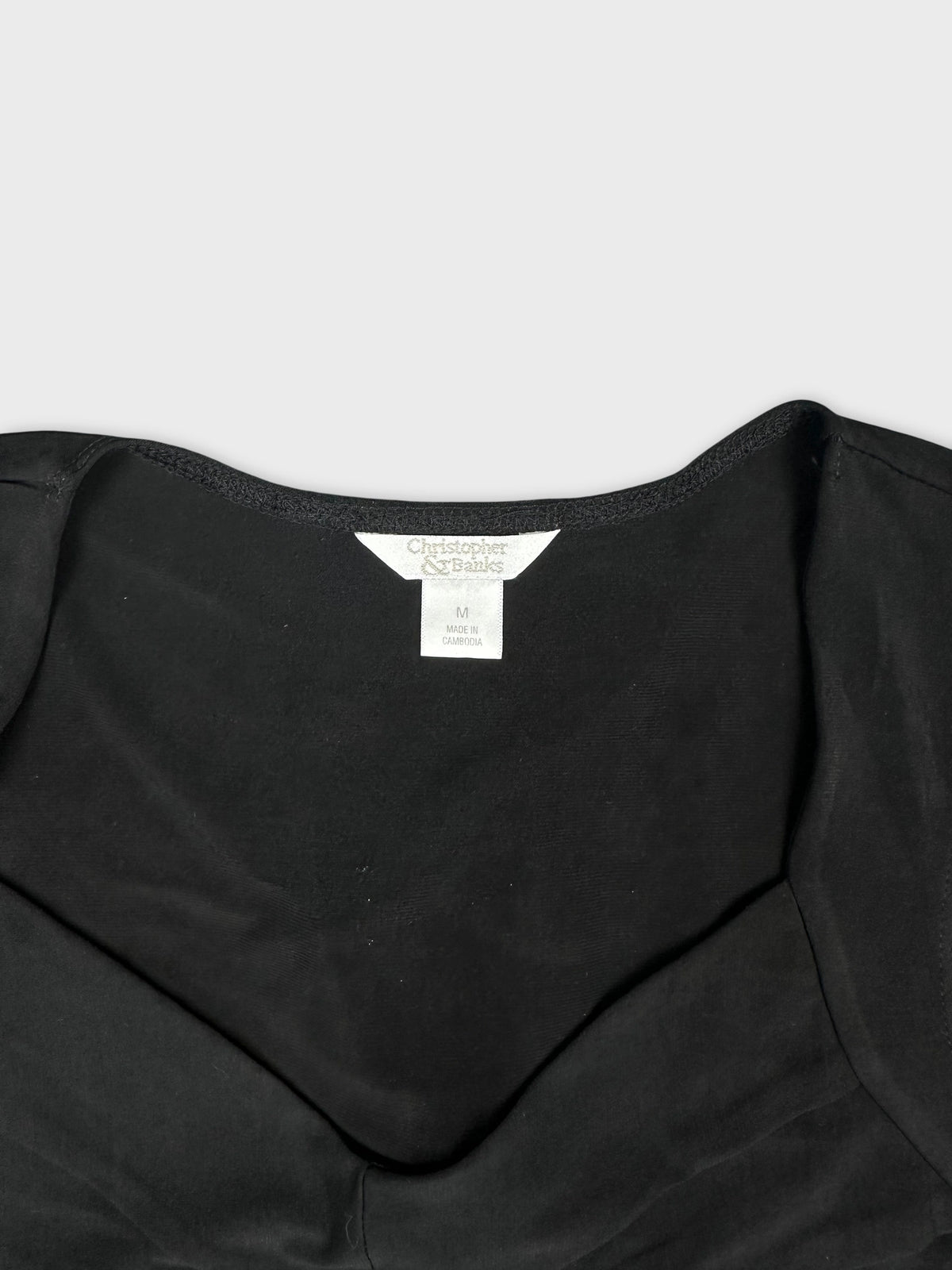Black upper body top with a scoop neckline detail view.
