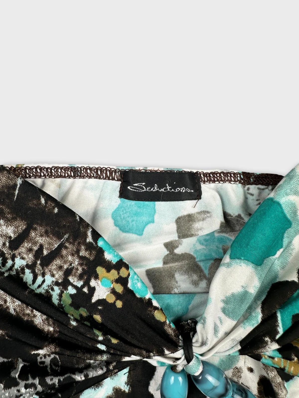 detail view of a vintage women’s top featuring a black and teal abstract pattern