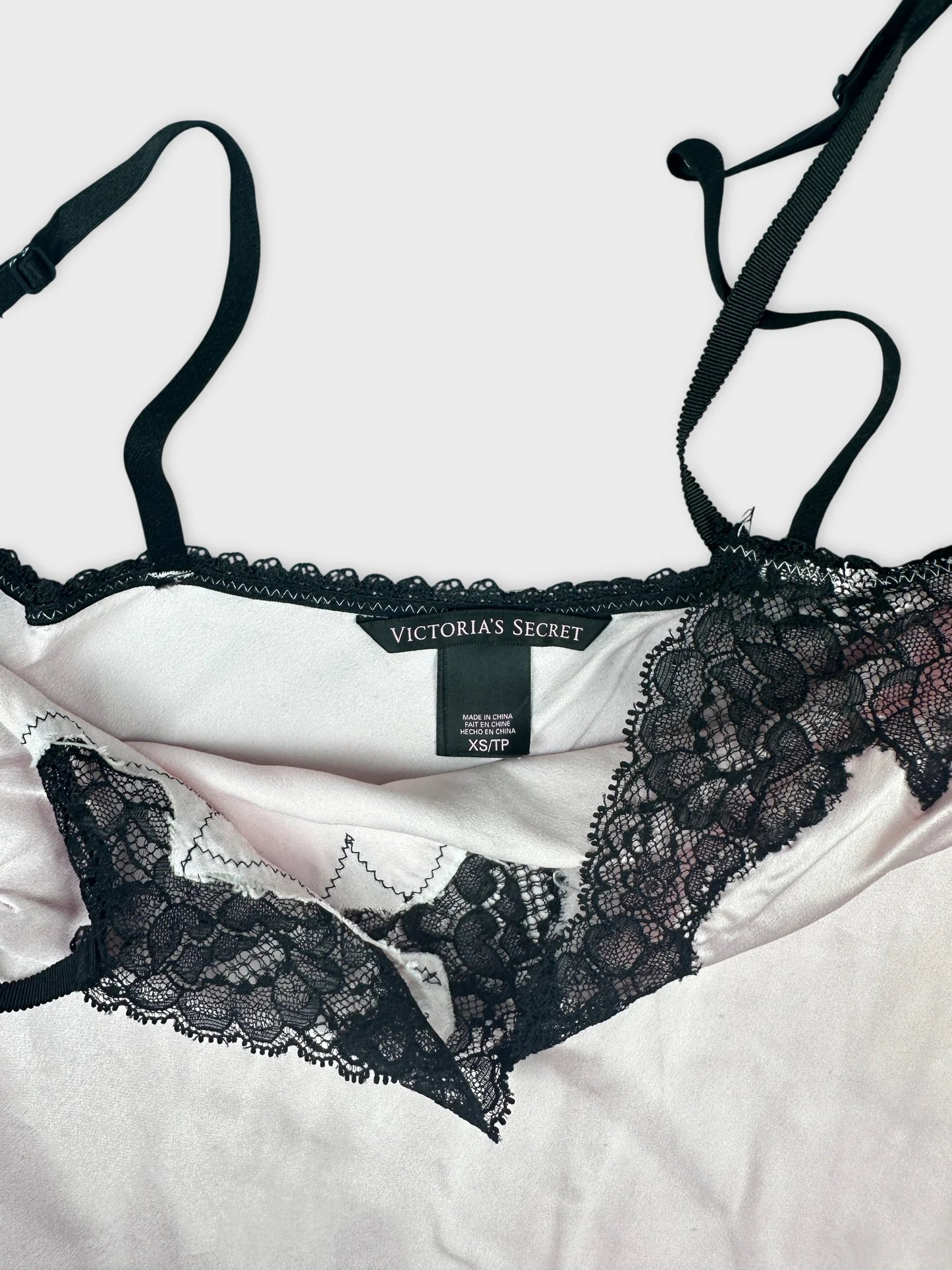 Detail view of a pale pink women's top with black lace trim.