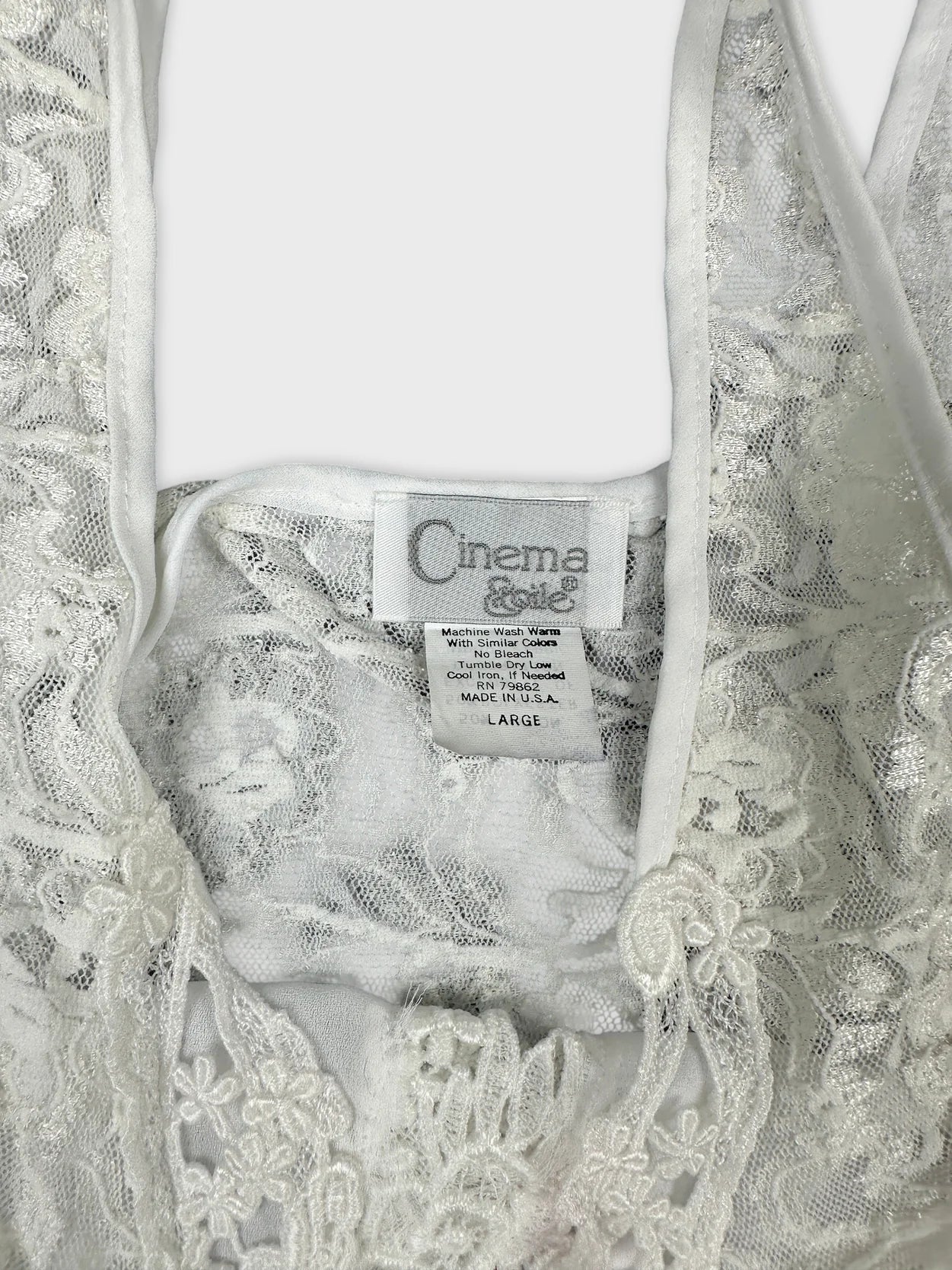 Detail view of a vintage white lace top showcasing intricate floral patterns.