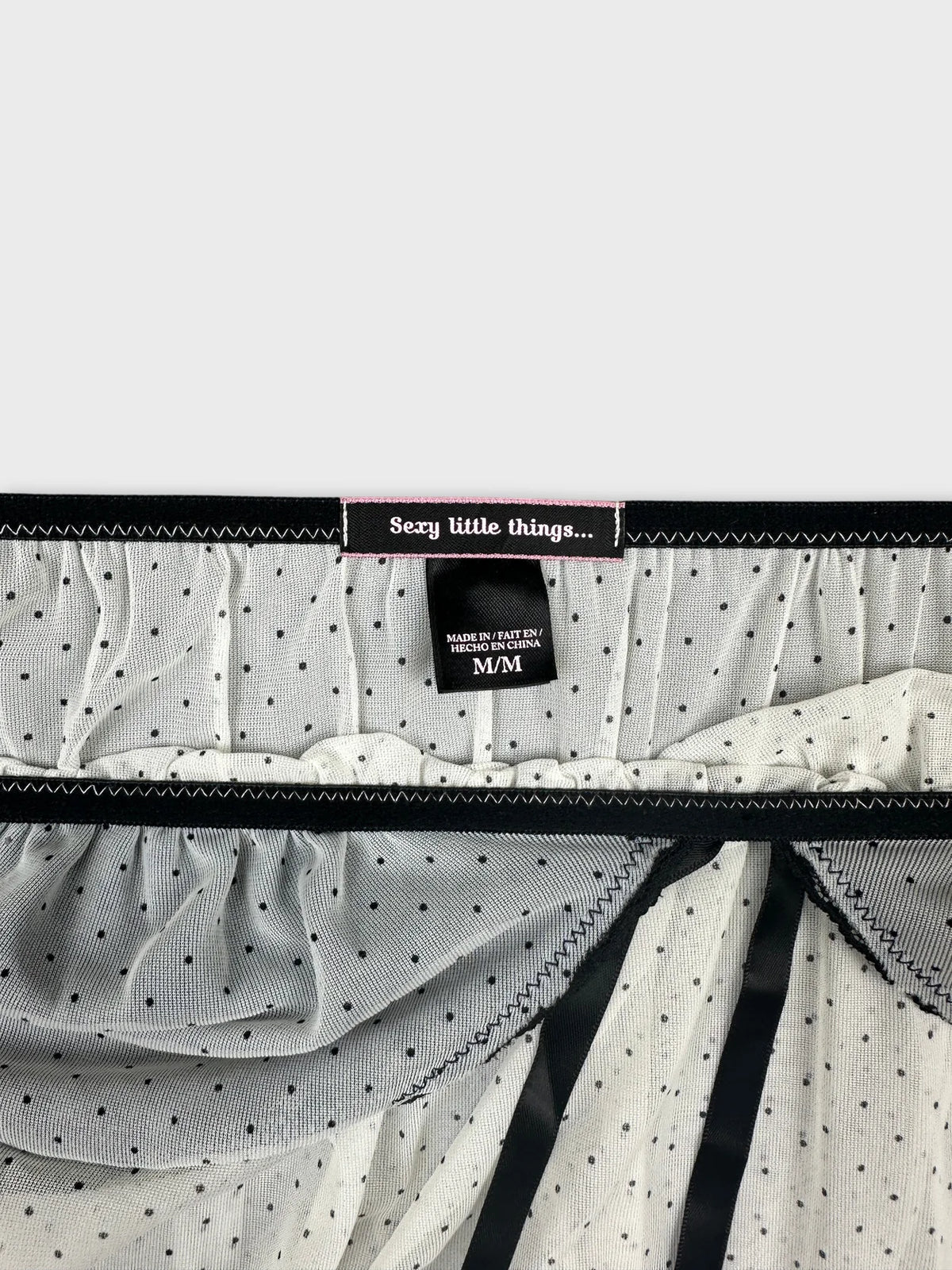 Detail view of a white dotted vintage top with black trim.