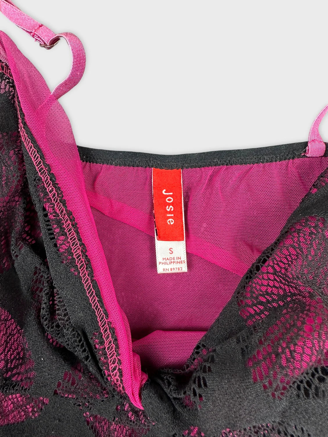 Detail view of a black top with pink lace trim design.