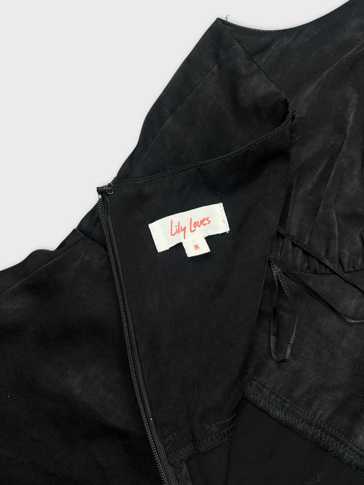 Black top detail view showing zipper and brand tag inside.