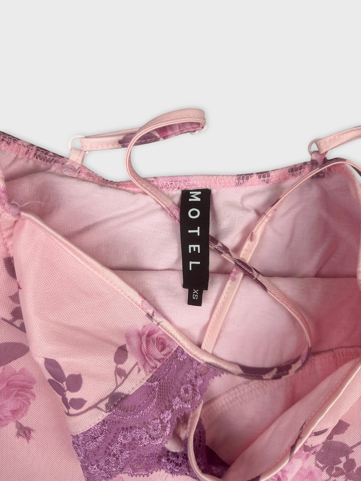 Detail view of a pink floral lace camisole with thin straps.