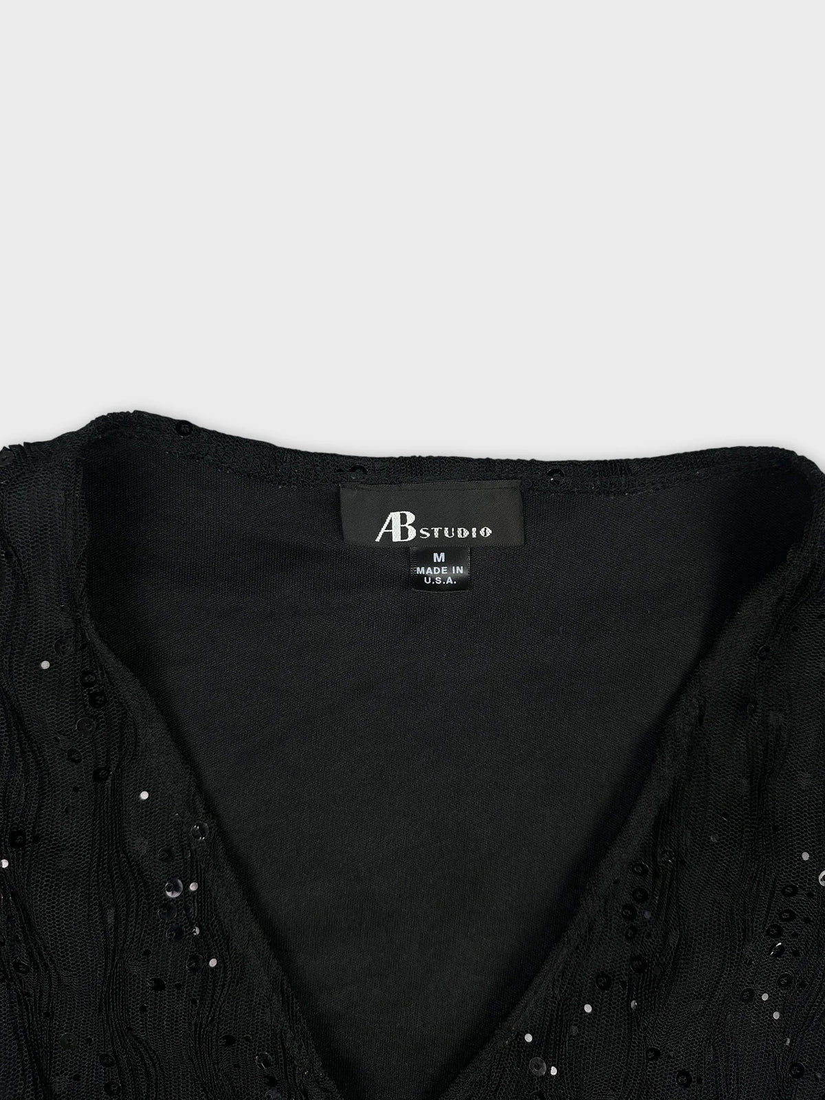 Detail view of a black vintage women’s top with textured sequined trim.