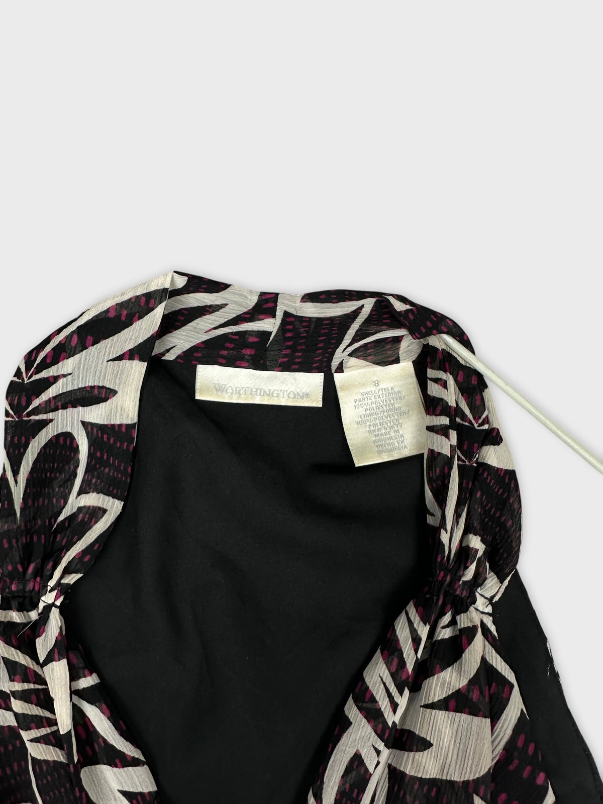 Detail view of a vintage black top with pink floral pattern.