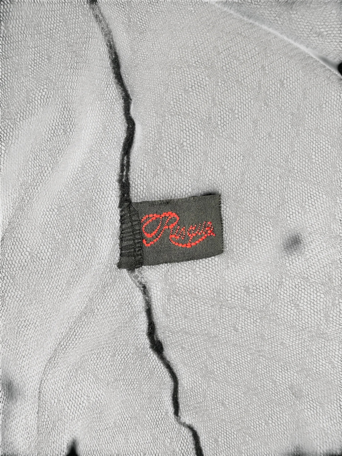 Detail view of a gray vintage top featuring a red printed label.