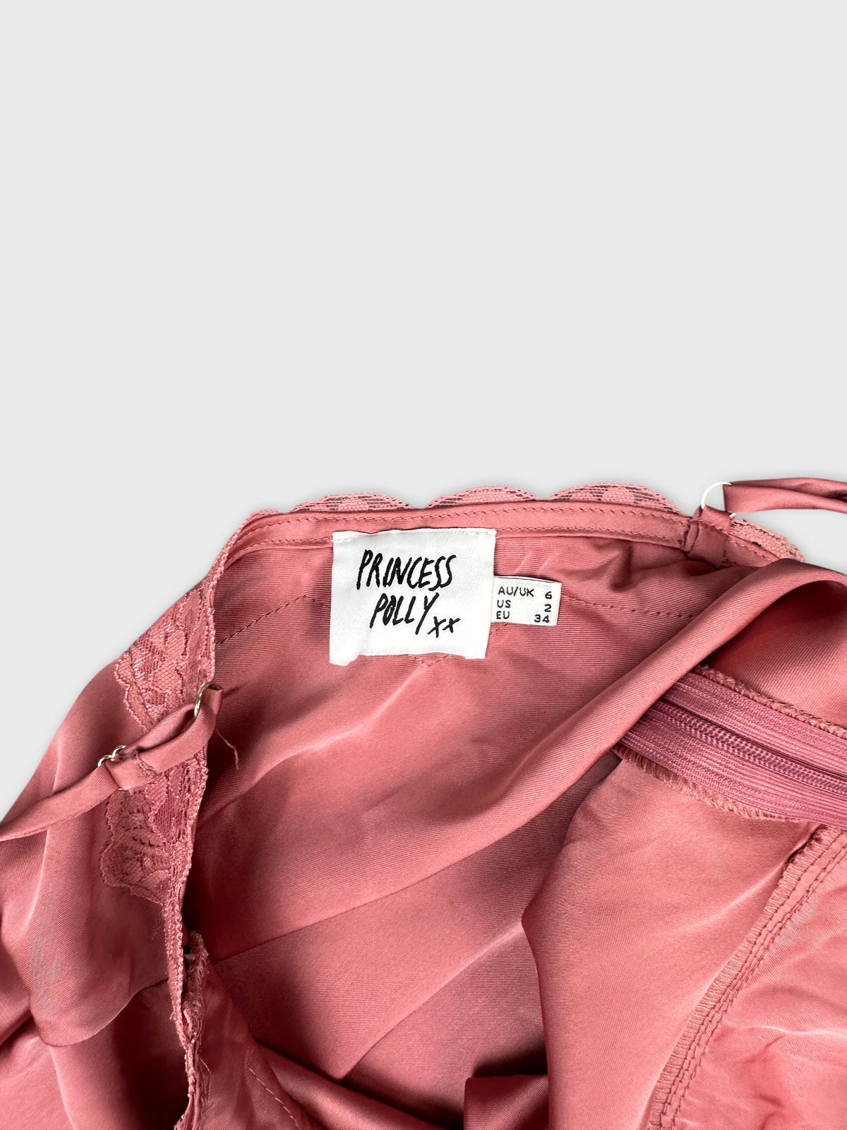 Detail view of a pink vintage top featuring lace trim and a zipper.