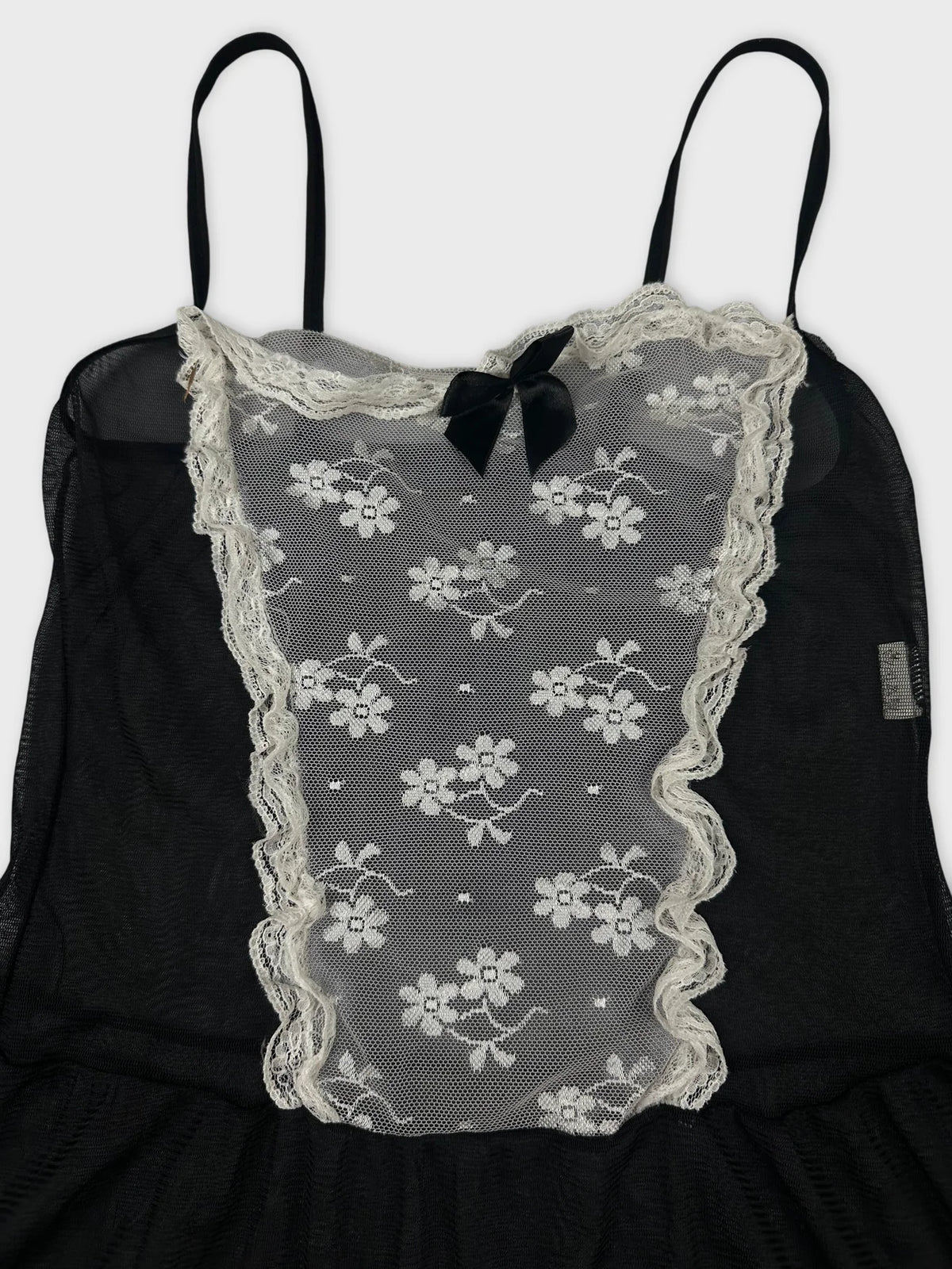 Detail view of a black vintage top with lace floral pattern and bow.