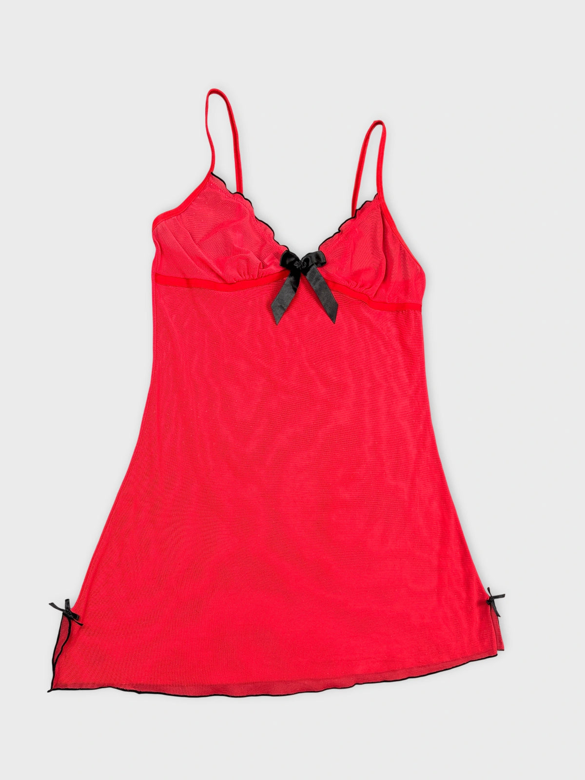 Detail view of a red spaghetti strap top featuring black trim and bows.