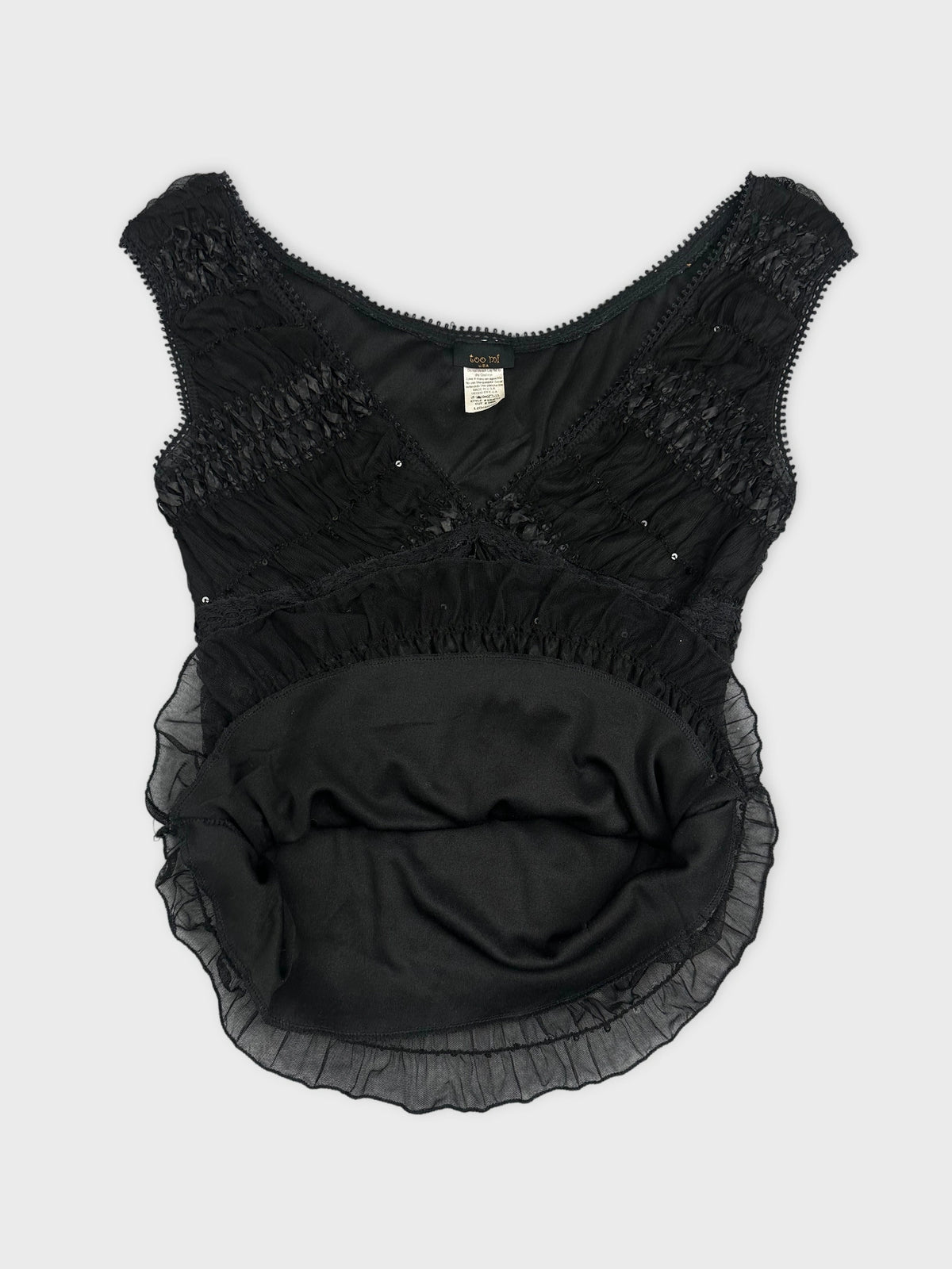 Detail view of a black vintage upper body top with ruffled trim.
