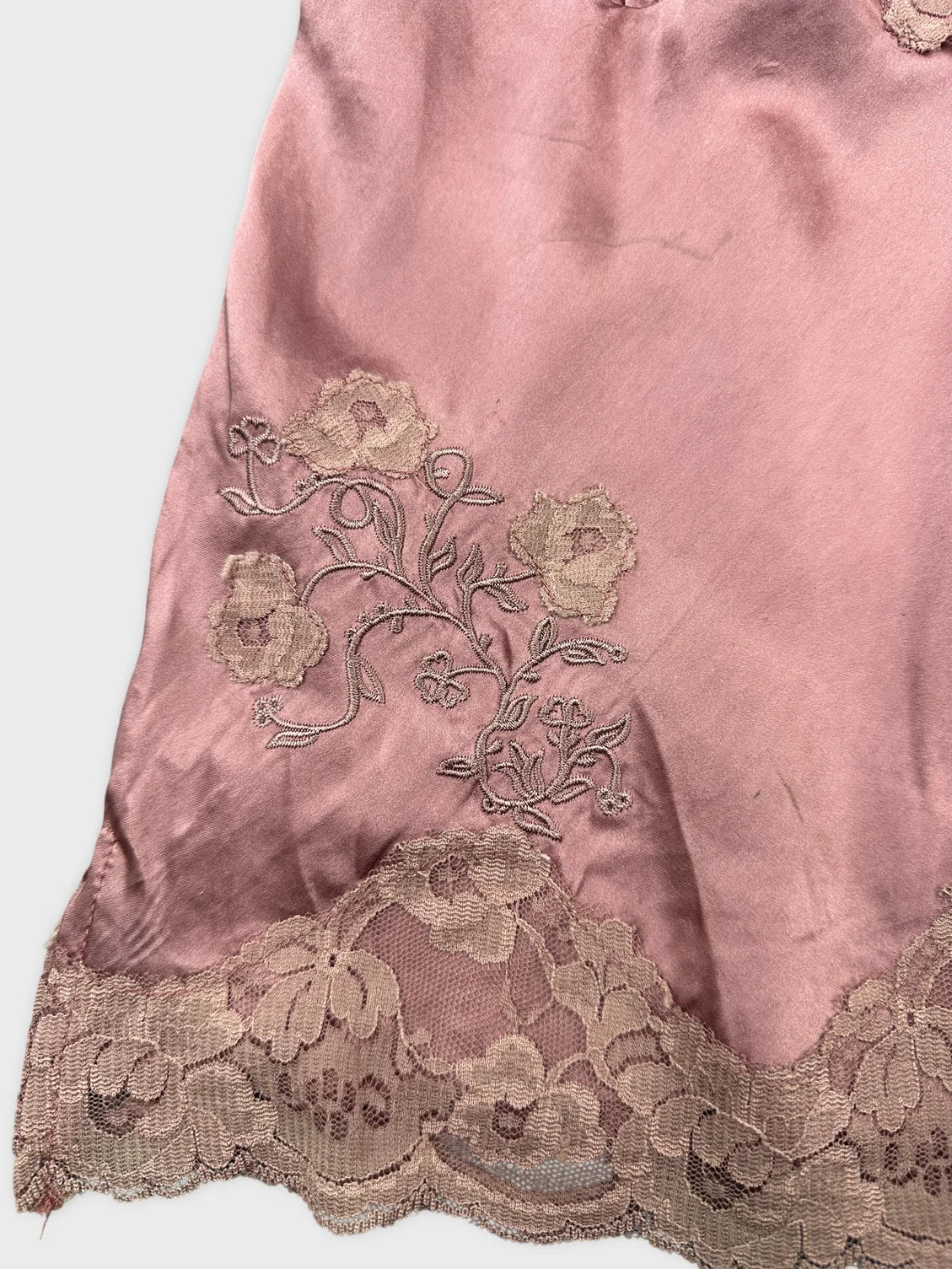 Detail view of a pink women’s top featuring floral embroidery and lace trim