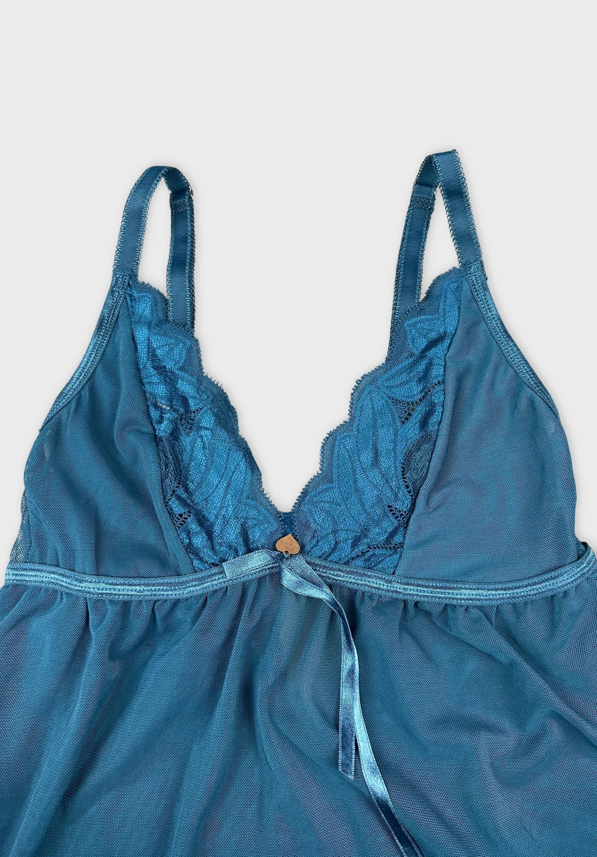 detail view of a teal women's top featuring lace trim and a bow tie.
