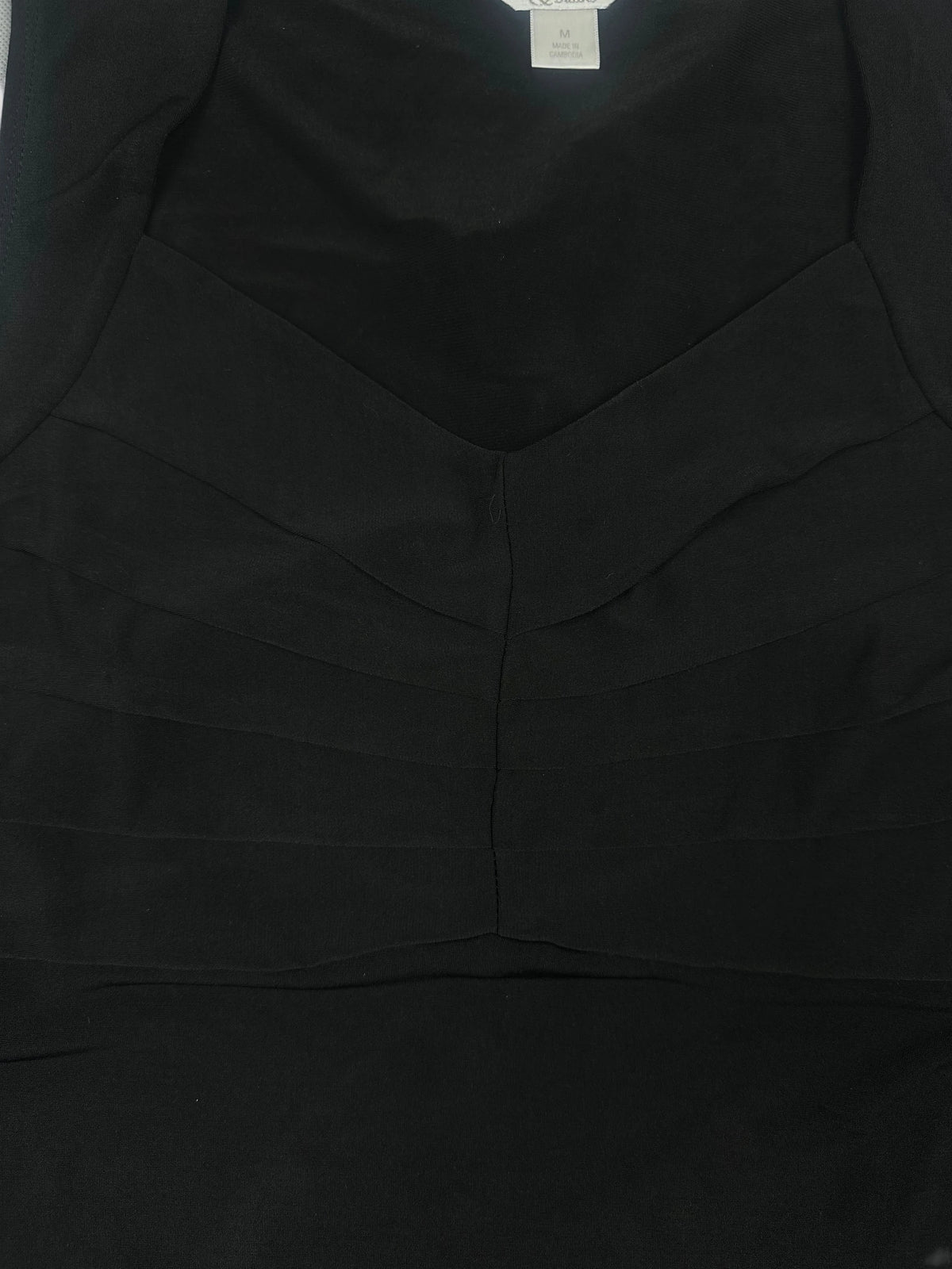 Detail view of a black upper body top with pleated design.