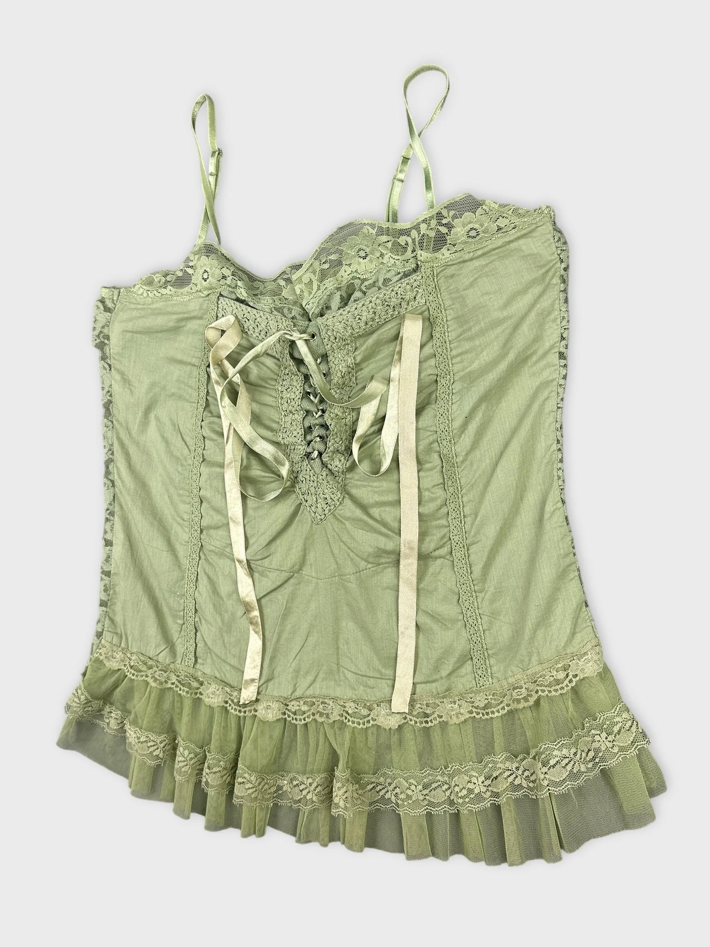 Detail view of a green women's top with lace trim and ribbon ties.