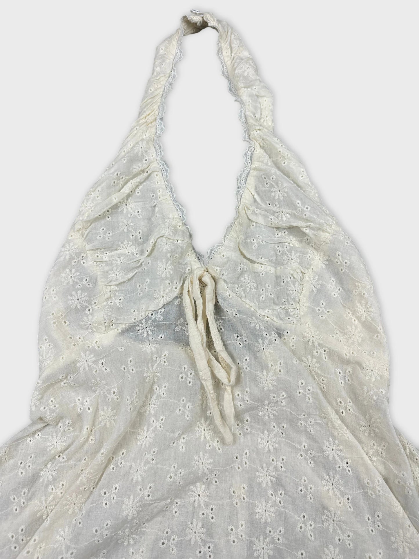 Detail view of a white halter neck top with floral embroidery.