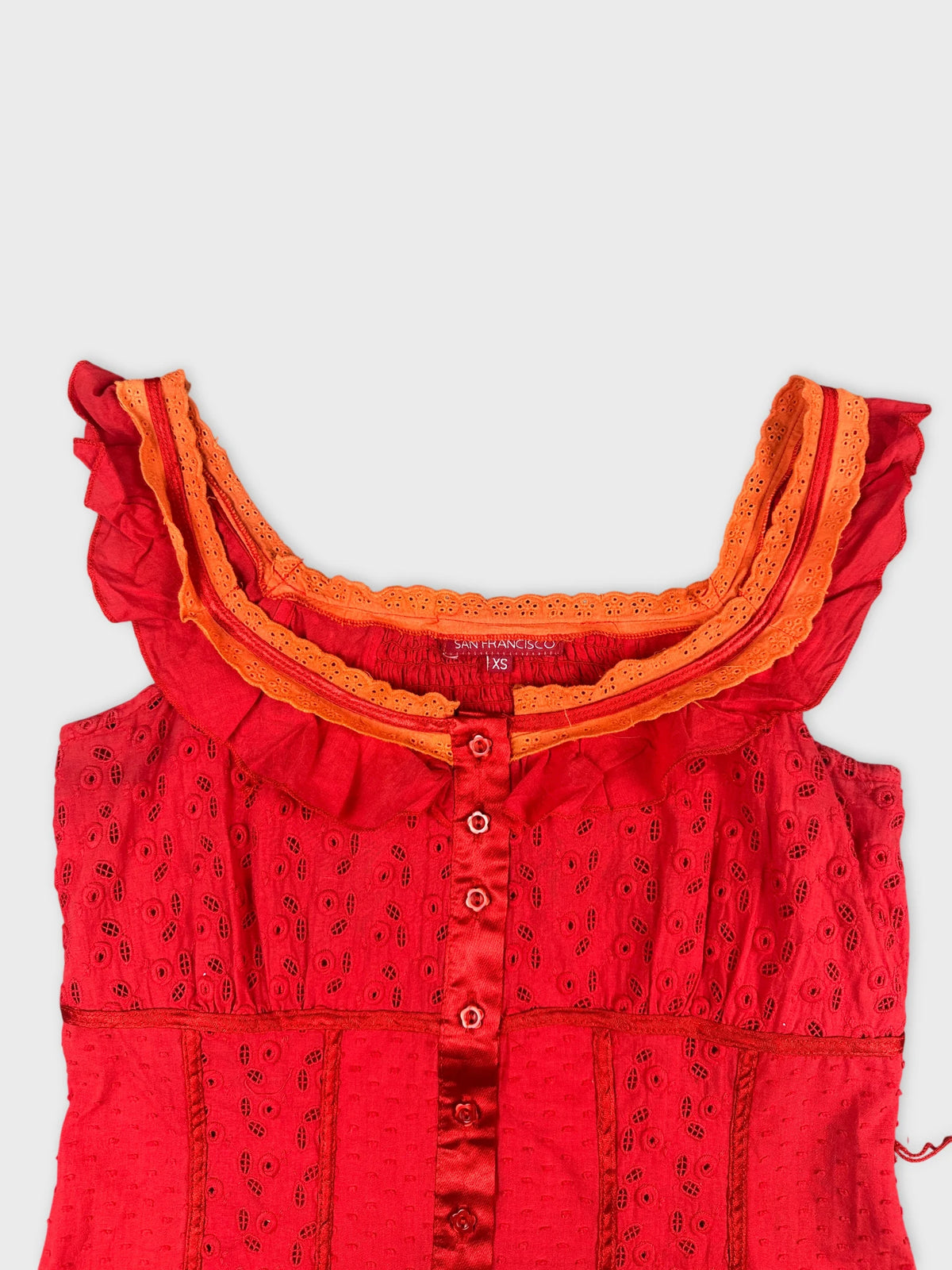 Detail view of a red vintage top with ruffled orange trim.