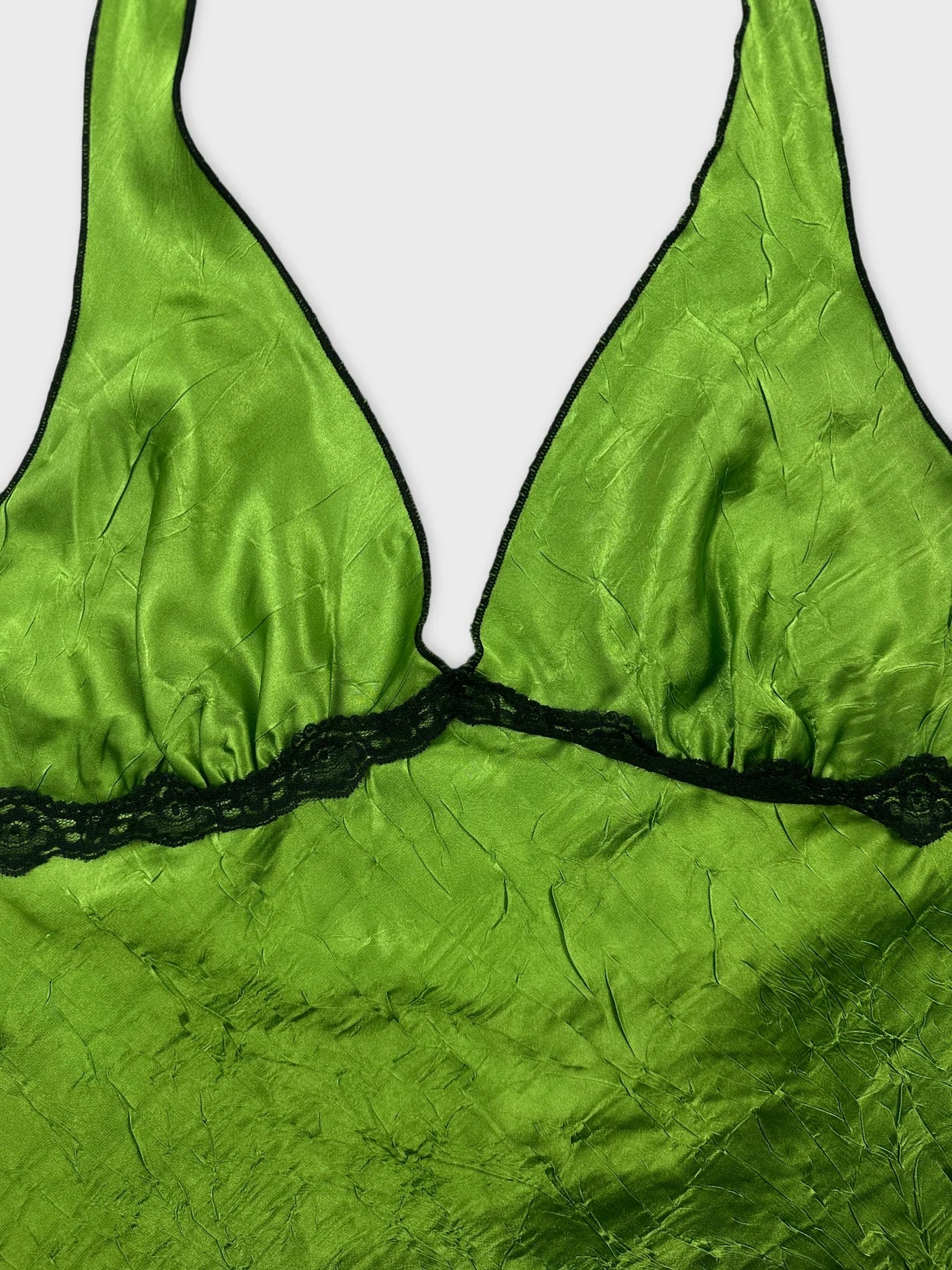 Detail view of a green satin upper body top with black lace trim.