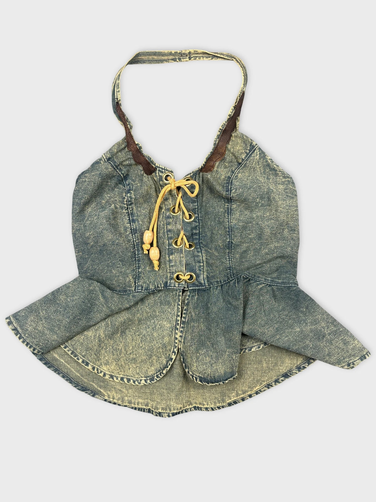 Detail view of a denim halter top featuring a peplum shape and lace-up front.